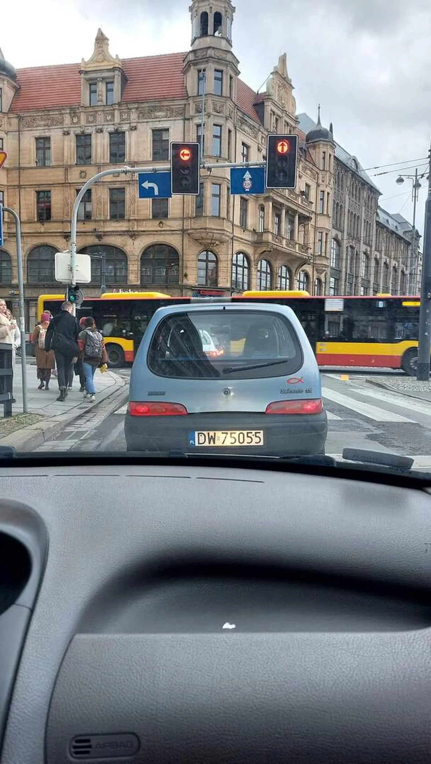 Kobieta około 50 lat staje koło mojego samochodu i robi dziwne miny w naszym kierunku (pasażer i kierowca), nastepnie próbuje zmienić pas (tylko z lewego można skręcać po zmianie organizacji ruchu) i wystawia rękę przez okno niejako prosząc o wpuszczenie. Następnie na placu Kościuszki zatrzymuje samochód mimo, że droga z przodu jest pusta, aby przepuścić samochód z drogi podporządkowanej!!!! Chwilę stoimy bo tamten kierowca i tak miał zablokowane skrzyżowanie i nie miał dokąd jechać. Następnie nie patrzy na żółte linie i przejeżdża na prawy pas, na który w myśl nowej organizacji ruchu powinny wjeżdżać bezkolizyjnie pojazdy z prawej strony. Wizyta u psychiatry przed otrzymaniem prawa jazdy powinna być obowiązkowa.