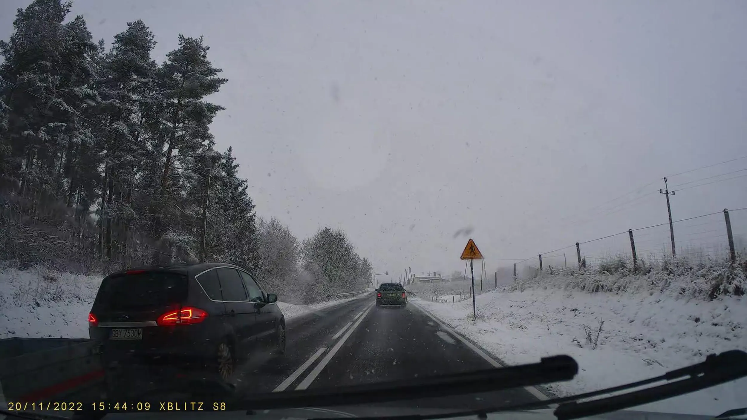 Kierowca z przyczepką wyprzedza kilka aut na ciągłej przed niebezpiecznym przejściem dla pierwszych. Nie zachowuje należytej odległości po zakończonym manewrze wyprzedzania. Nie dość, że ślizgo i pada śnieg, to i ryzykuje czyimś życiem.