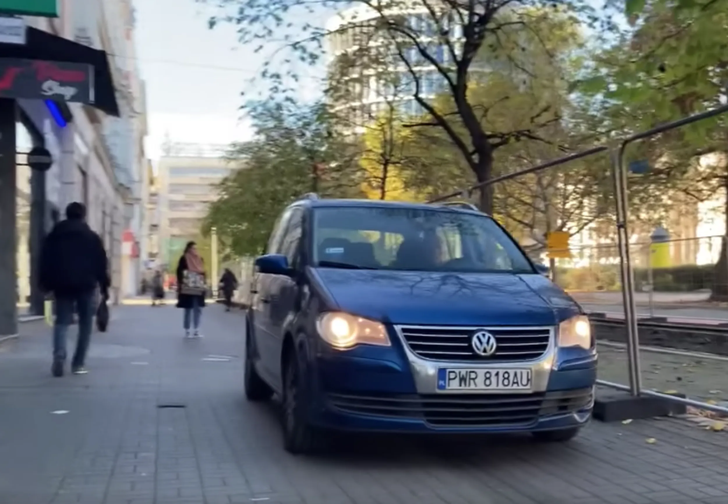 jeździ po mieście po chodniku wśród chodzących ludzi.