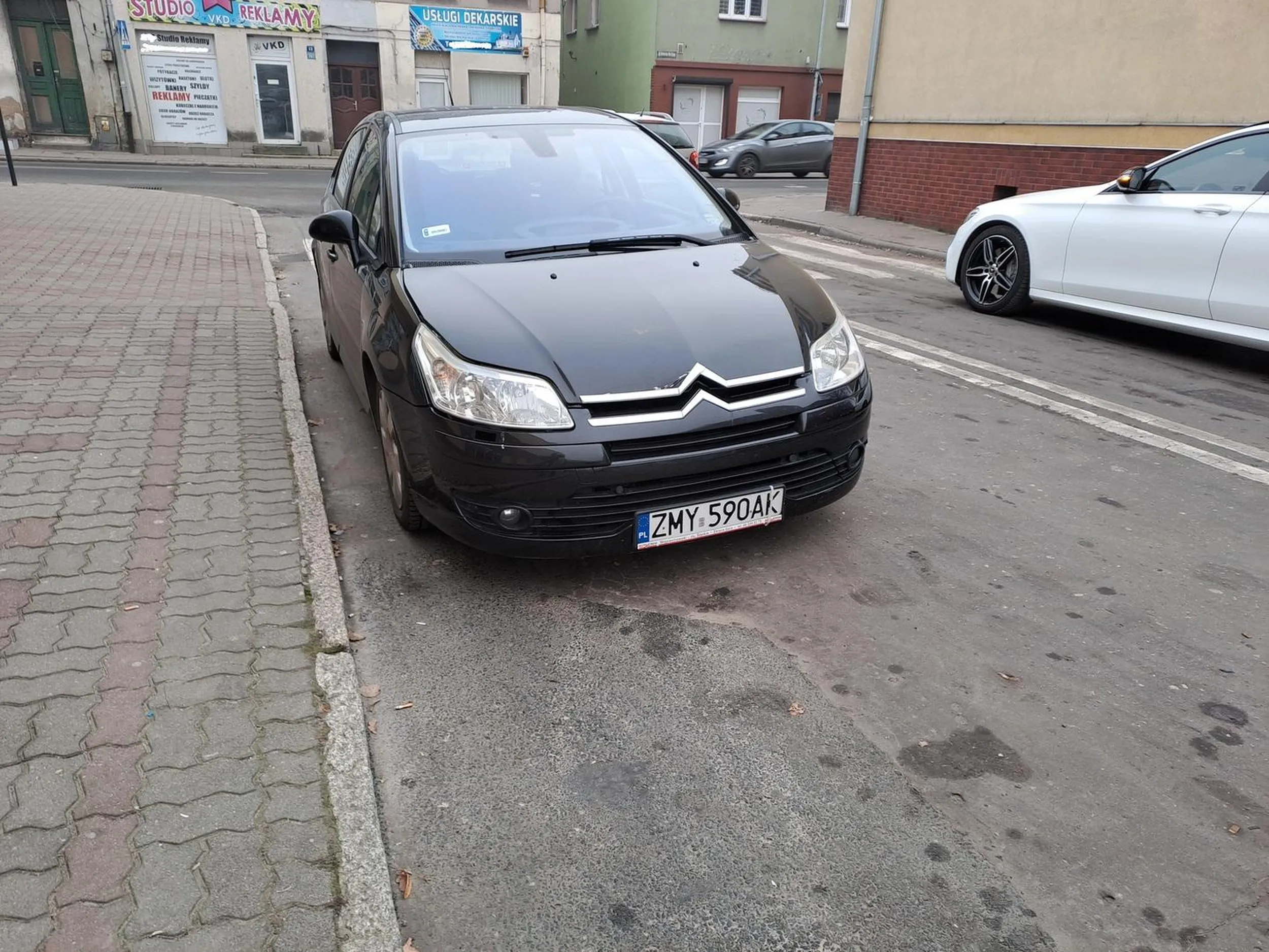 Parkuje zasłaniając przejście dla pieszych jednocześnie zmuszając innych kierowóców do przekraczania osi jezdni oznakowanej podwójną linią ciągłą.