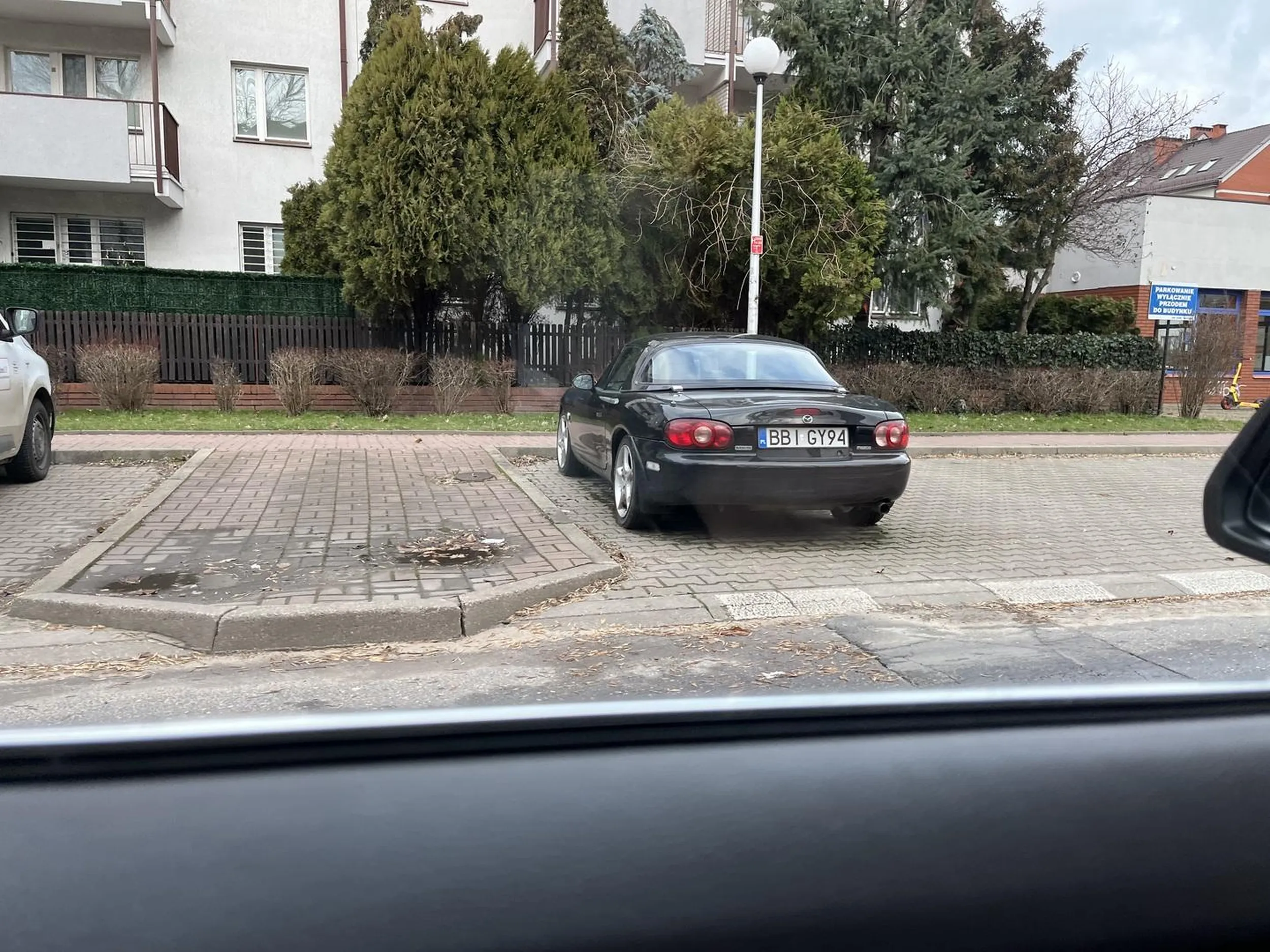 Mazda MX-5 NBFL z numerem rejestracyjnym BBI GY94. Pozostawiona na parkingu przy ulicy Wolumen 18 w Warszawie. Stoi tak od kilkunastu miesięcy. Wygląda jak porzucona.