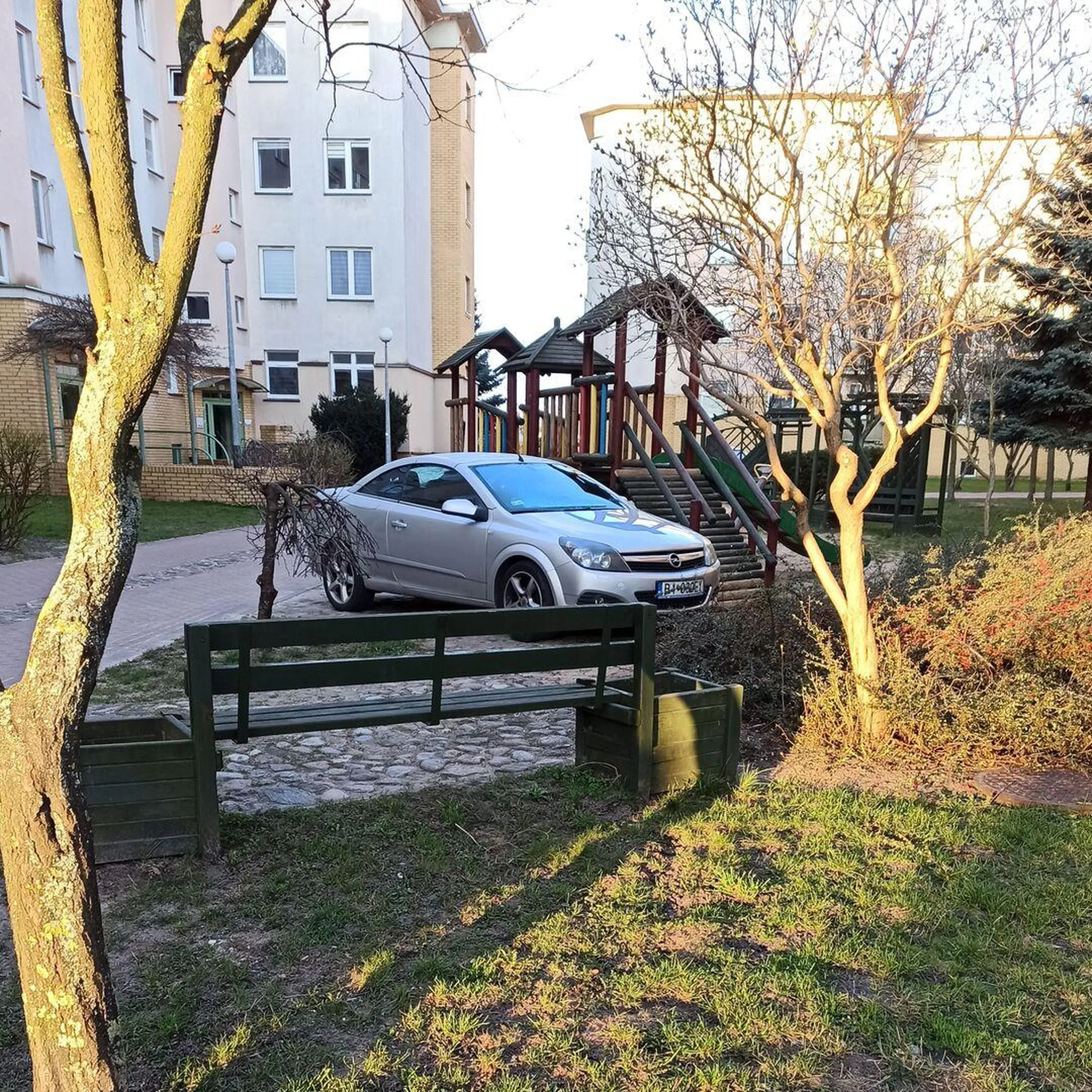 Gdyby kierowca miał pieniądze na zakup terenówki, to pewnie by wjechał na zjeżdżalnię, żeby tylko zaparkować jak najbliżej klatki wejściowej. A tak to musi się zadowolić parkowaniem starą Astrą obok kosza na śmieci, z widokiem na smutne dzieci, które nie mogą korzystać z placu zabaw.