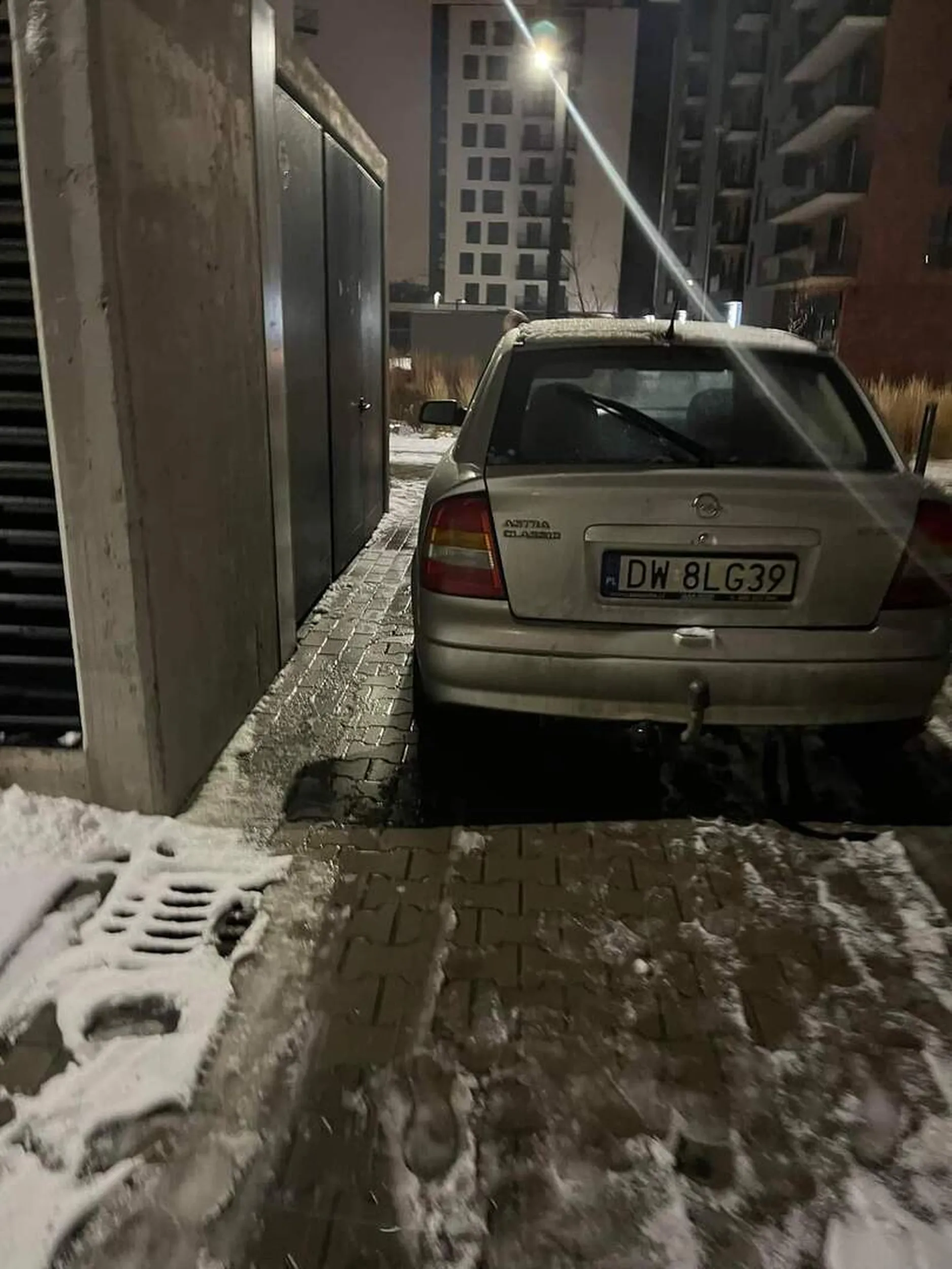 Samochód chyba jest w kiepskim stanie technicznym, bo leży pod śmietnikiem. Właścicielu: blokujesz wejście do wiaty śmietnikowej, a także zastawiasz drogę przeciwpożarową.