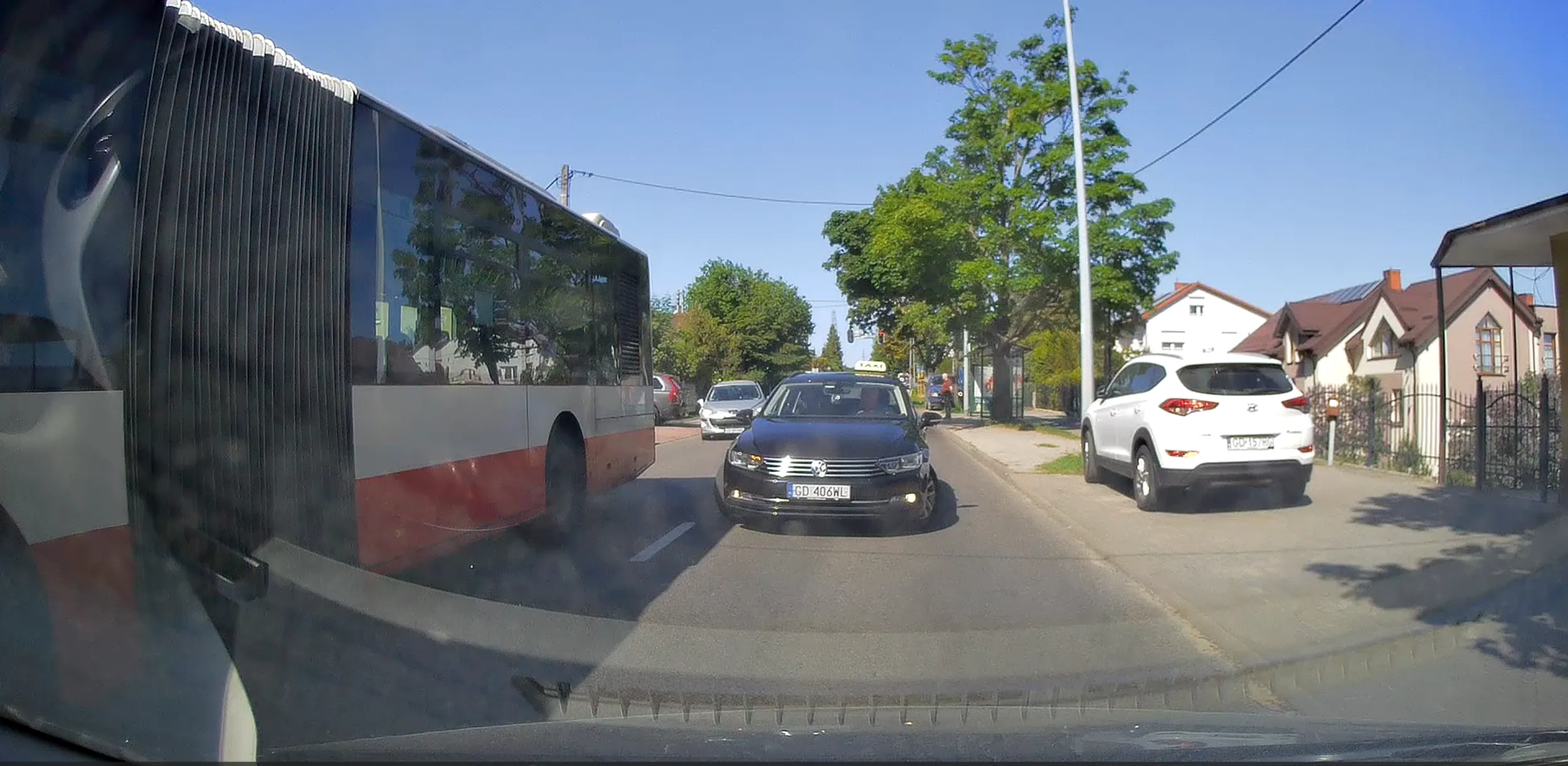 Kierowca taksówki chce ominąć autobus stojący w korku i na przystanku, wymuszając pierwszeństwo i tamując ruch