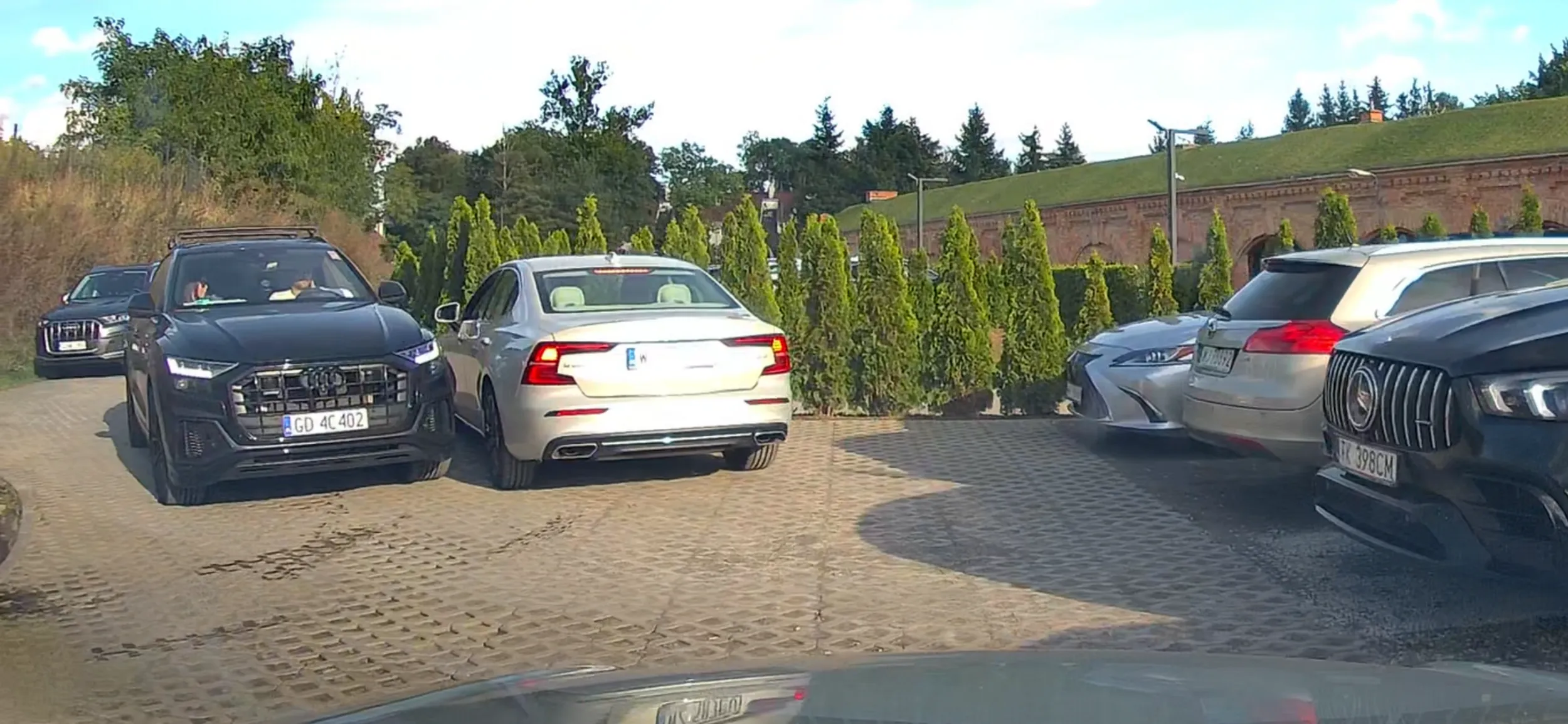 Fort Służew w Warszawie, weekend, mało miejsc i ciasno na parkingu. Pan kierowca jak na zdjęciu stanął na zakręcie i nie chciał się ani centrymetr ruszyć (na zdjęciu widać że ma jeszcze chyba z ponad pół metra do krawędzi drogi), kobieta w volvo gimnastykowała się aby wyjechać z parkingu. Stał tak dopóki się nie przecisnęła. Kierowca albo ma manię wielkości i myśli że ma większy sprzęt (auto) niż w rzeczywistości i nie ogarnia jego wymiarów, aby zjechać do krawędzi drogi, albo jest po prostu bucem i lubi utrudniać innym życie. P.S Zasada jest, że najpierw wypuszczą się wychodzących, aby w środku było miejsce i można było wejść, podobnie powinno być z parkingami.