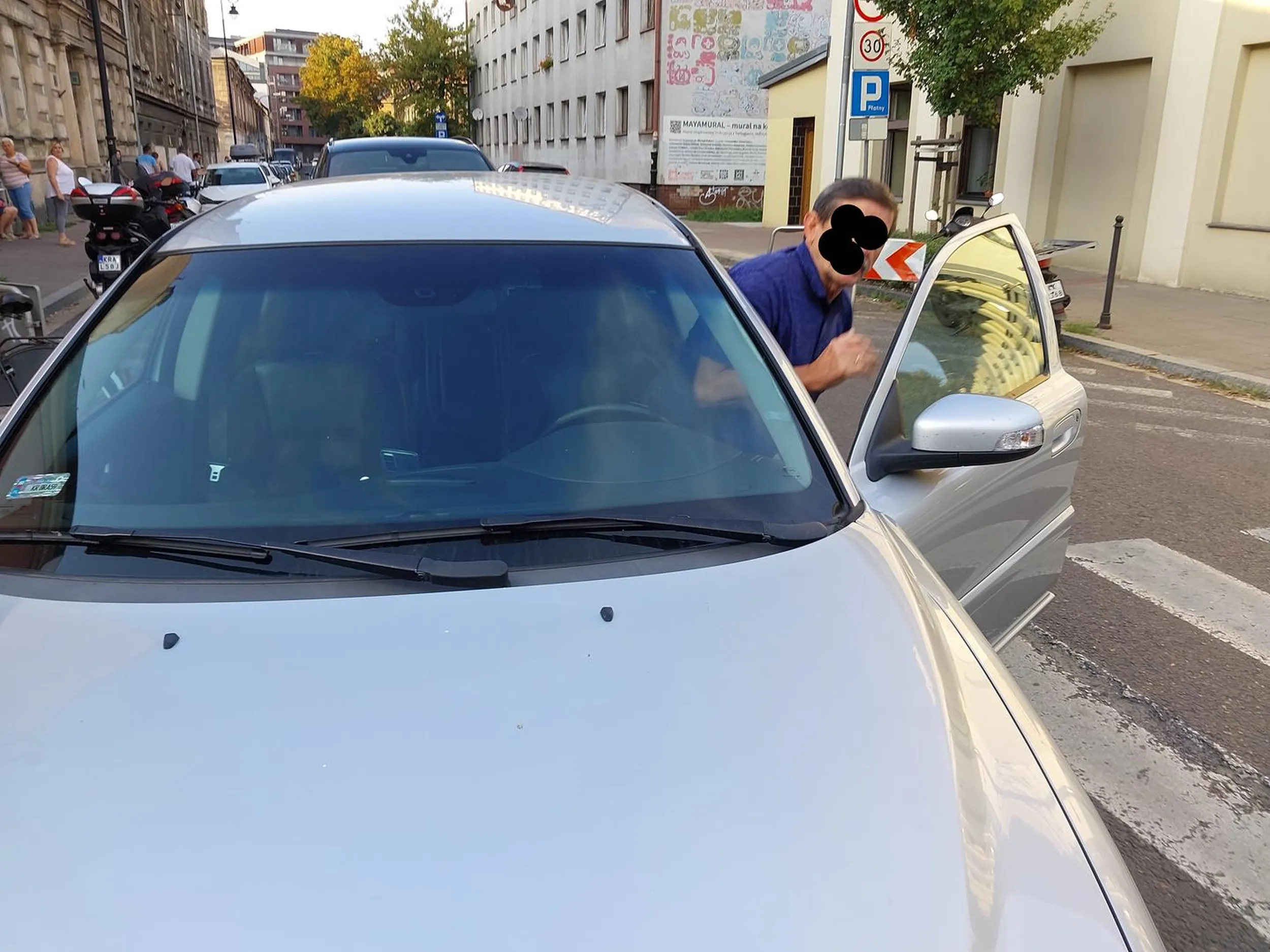 Kraków (2023-09-13 godz: 17:20) róg ulic: Limanowskiego i Krakusa. Kierowca skrecał z Krakusa w prawo w Limanowskiego. Wjechał poza połowę przejścia dla pieszych, a ja już chciałem wejść na przejście, nie zatrzymałem się i zacząłem wchodzić na przejście po czym on jeszcze podjechał ok pół metra i dopiero się zatrzymał. Następnie wszedłem na przejście stanąłem przed jego autem (srebrne Volvo) i popatrzyłem się na niego. Wówczas psychopata zaczął wymachiwać do mnie rękami, więc ja też machnąłem, że coś zrobił nie tak, wtedy otwiorzył szybę i zaczął krzyczeć wi ęc mówię, że wymusił pierwszeństwo pieszemu. Po krótkiej kłótni, otworzył drzwi i częściowo wyszedł z auta, wyjmując coś ze schowka w drzwiach. Gdy podniósł rękę okazało się, że ma w ręćę gaz i zaczał machać tak, że zagroził mi użyciem gazu przeciwko mnie. Wówczas krzyknałem że zaraz moge wezwac Policję i zrobiłem zdjęcia, które załaczam. Rozważe teraz czy zgłosić to na Policję - to jest beznadziejny prostak, który powinien iść za 