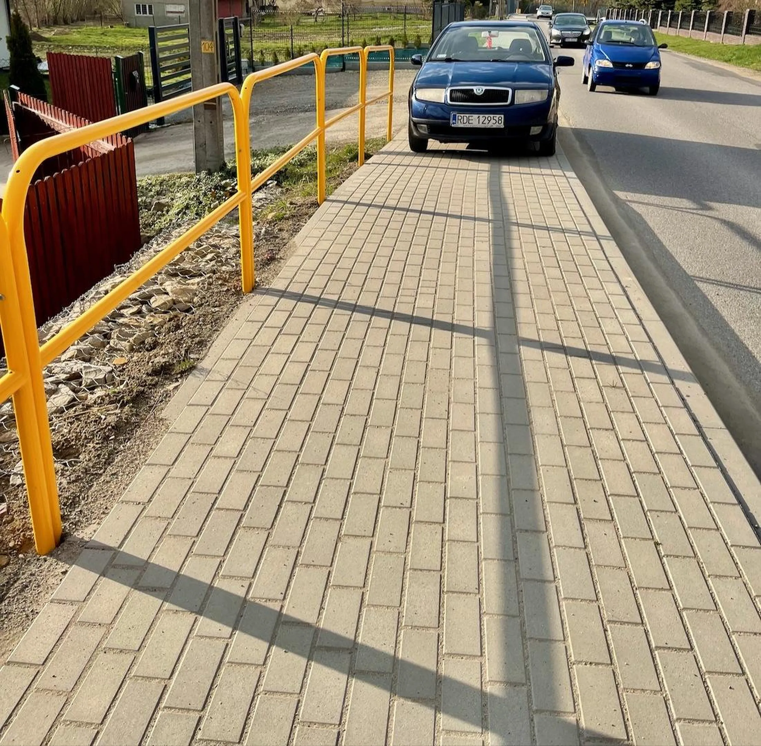 Osoba parkująca Skodą niszczy chodnik oraz zajmuje całą jego szerokość. Auto znajduje się na zakręcie i sprowadza niebezpieczeństwo na ludzi, którzy spacerują chodnikiem. Za II RP tak nie było!