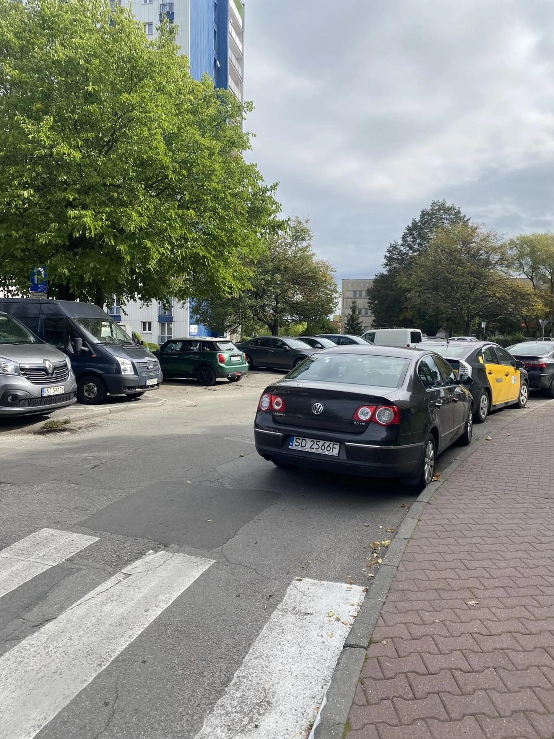 Kierowca z samochodu postanowił zaparkować przy samym przejściu dla pieszych, tak aby specjalnie zablokować ruch w jedną stronę i utrudniając widoczność pieszym tylko po to, aby mieć 5 kroków na targ. Bardzo nam przykro, że nie może Pan/Pani wjechać jeszcze na targ, ale te 5 kroków z miejsca parkingowego (które jak widać na zdjęciu były dostępne) mogłyby pomóc. Niestety otyłość w tych czasach jest dużym problemem, dlatego mieszkańcy osiedla polecają ruszyć d*pę i zaparkować jak każdy człowiek, a nie k*tas.