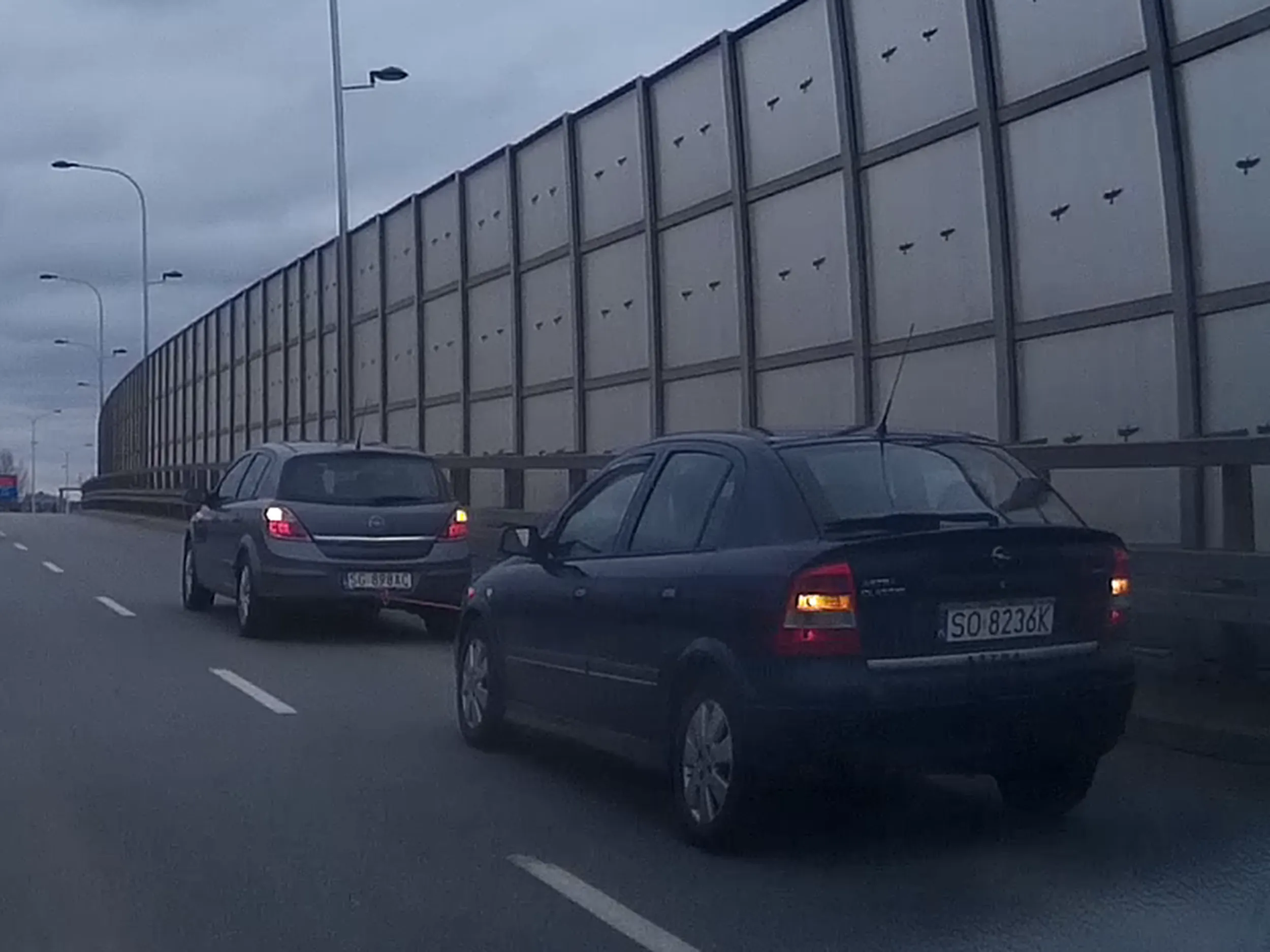 Dwa pajace nie potrafiące holować samochodu. Nie dość, że nie założyli trójkąta na holowany samochód, to jeszcze zarówno holowany jak i holujący mają niepotrzebnie włączone światła awaryjne. Bardzo ciekawe jak sygnalizowali zmianę pasa...