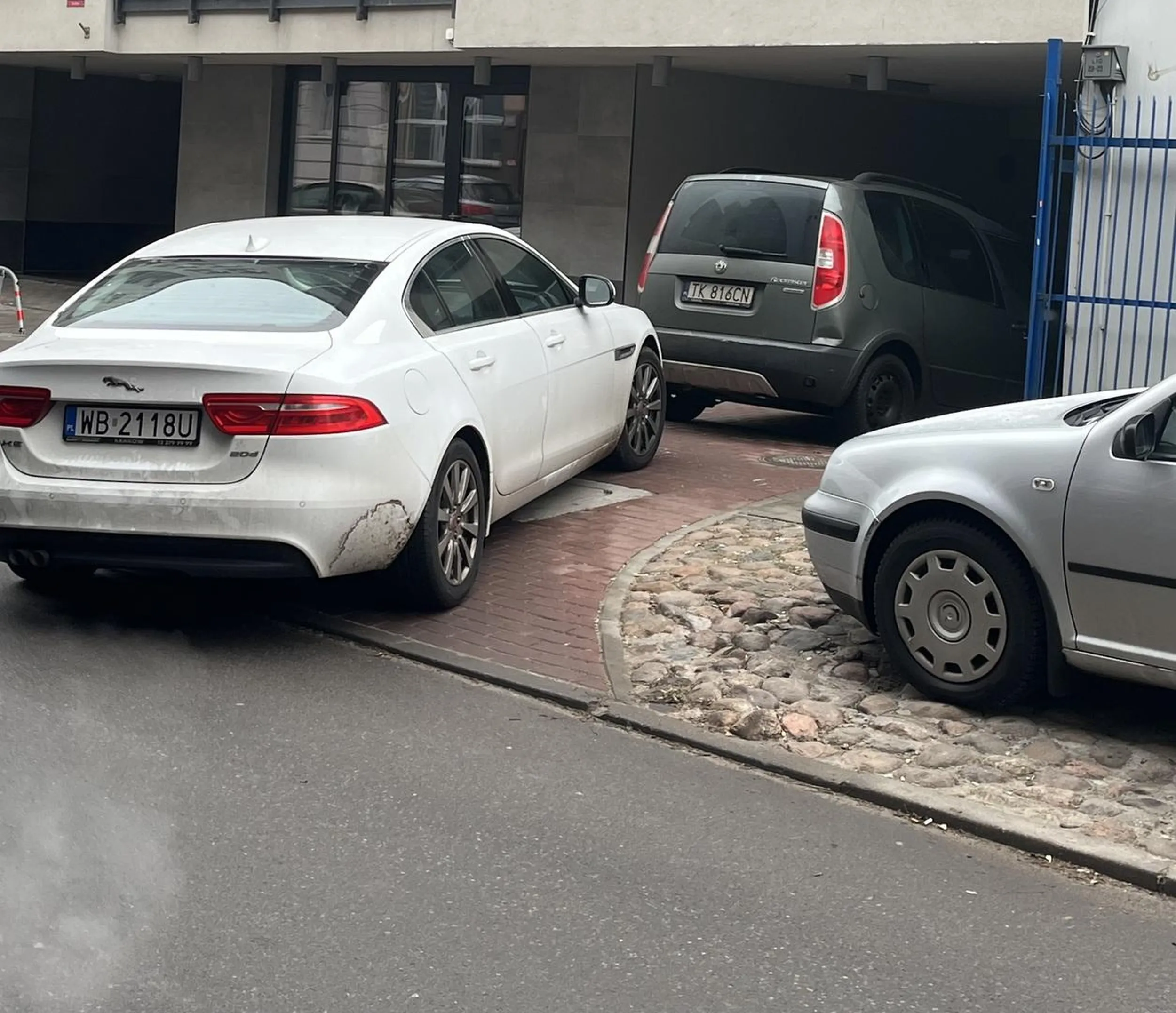 Blokuje wjazd do prywatnego garażu w bloku wielorodzinnym, zastawia przejście pieszym, solidnie wystaje tyłem samochodu na ulicę.