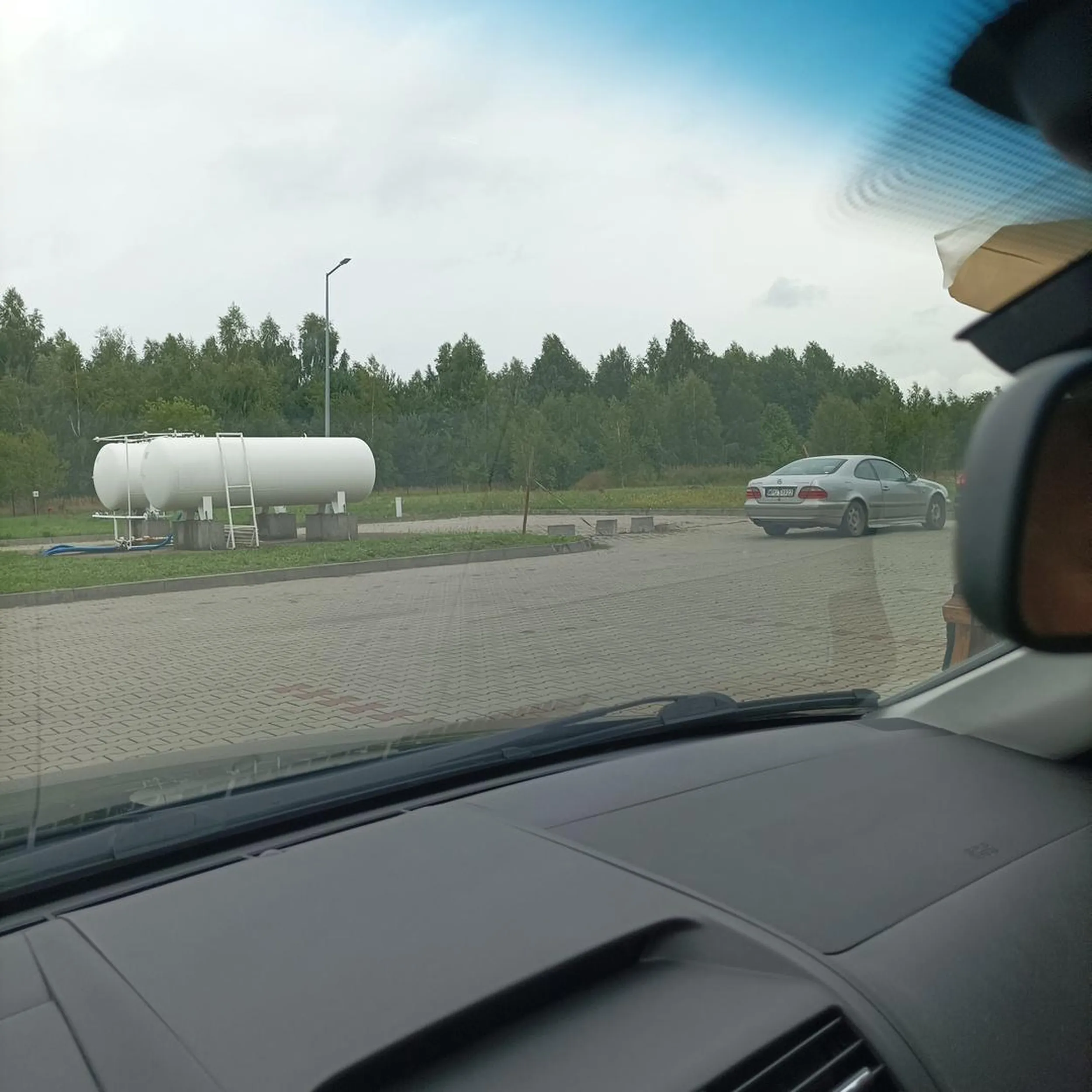 Gość "driftuje" i kręci bączki na stacji benzynowej wokół dystrybutorów.