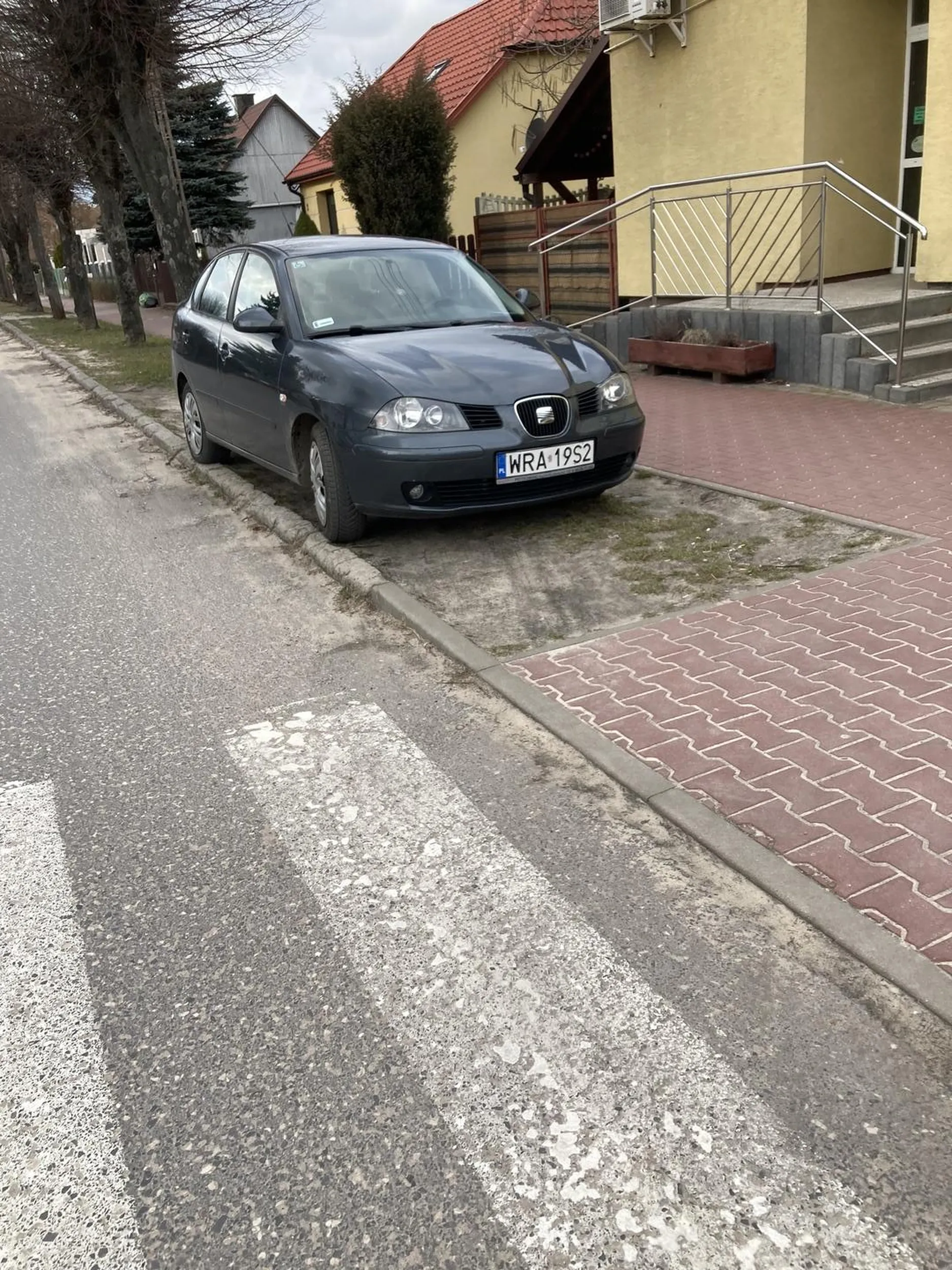 Pionki, ulica Kozienicka. 15.03.2023, godzina 15:10 Tak to chyba się nie parkuje. Trawa, obok przejście dla pieszych.