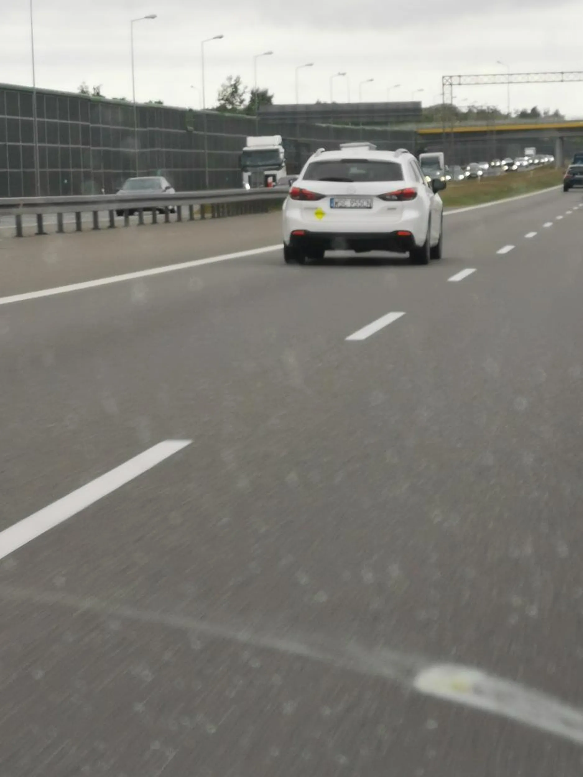 Dwóch gamoni w czapeczkach wychamowuje auto na drodze ekspresowej