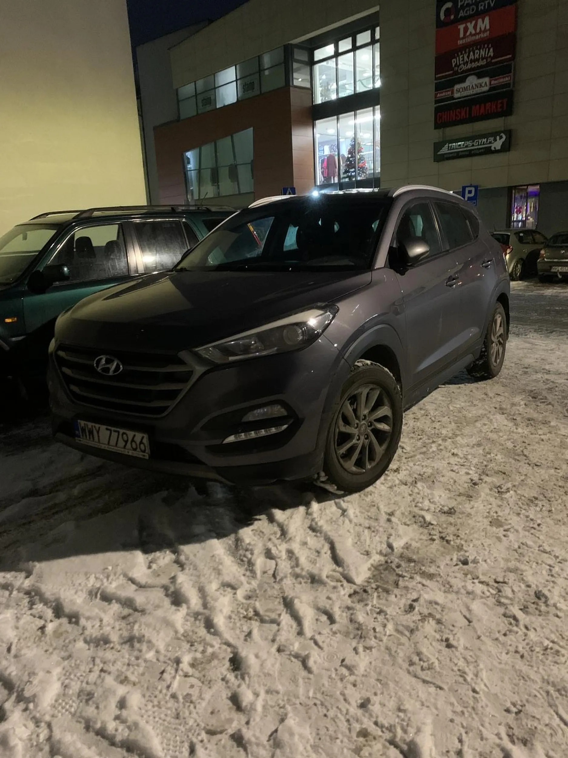 Kierowca parkuje samochód we wjeździe na parking. Nota bene parking był dla mieszkańców bloku na przeciwko galerii.