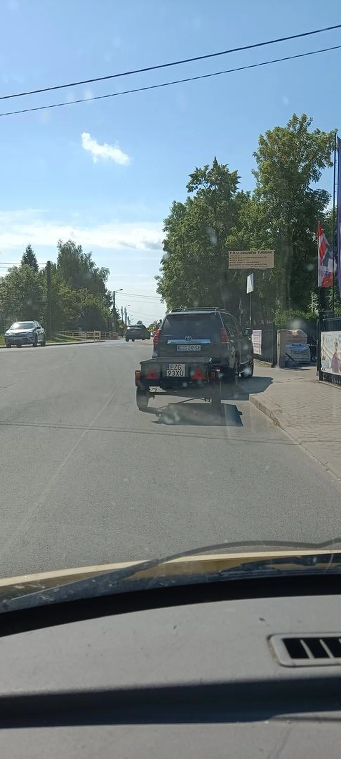 Parkuje z przyczepka blokując wjazd i wyjazd ze sklepu dodatkowo uniemożliwia wyjazd z drogi podporządkowanej