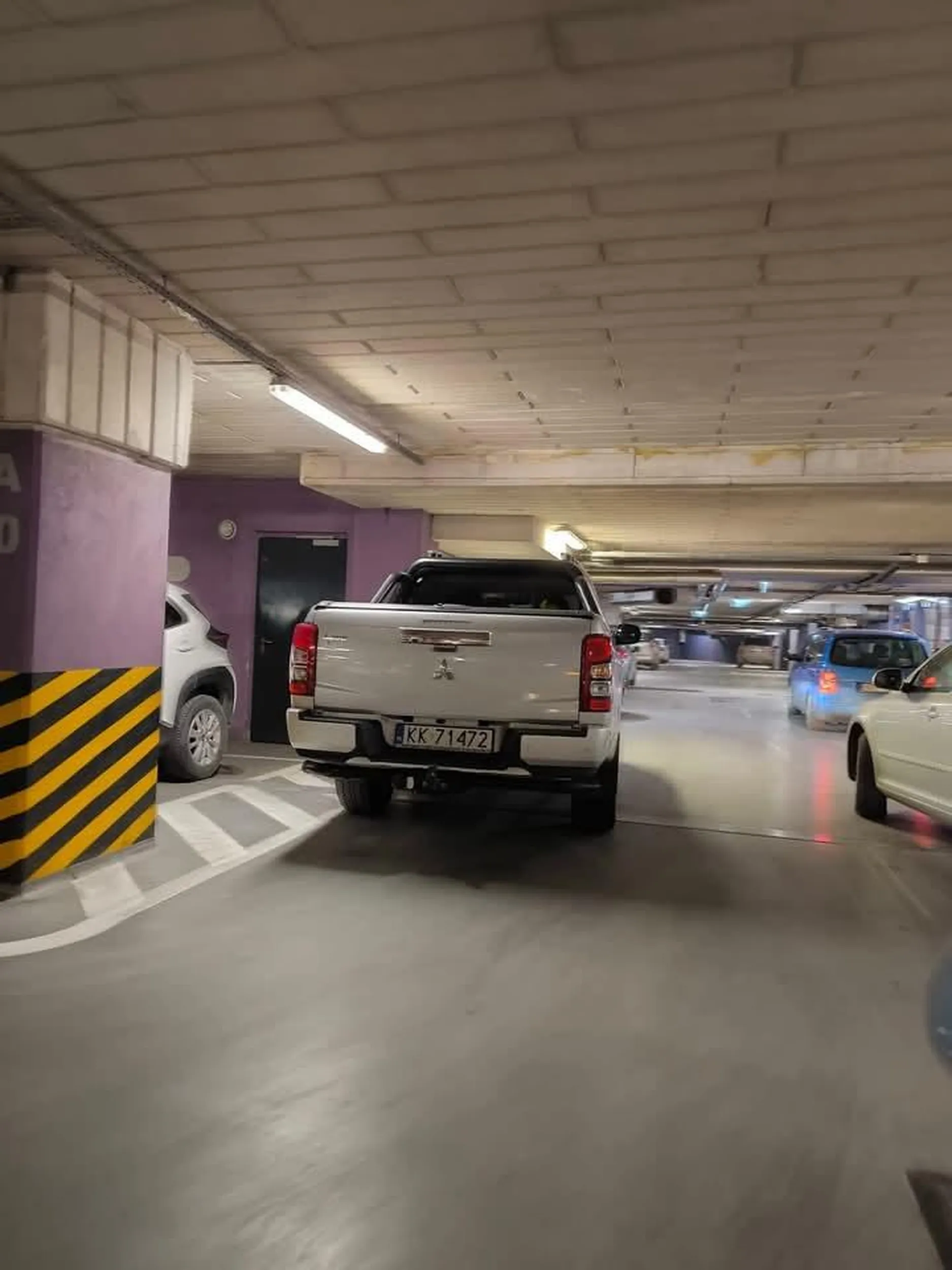 Pięknie parkuje na środku przejazdu na parkingu.