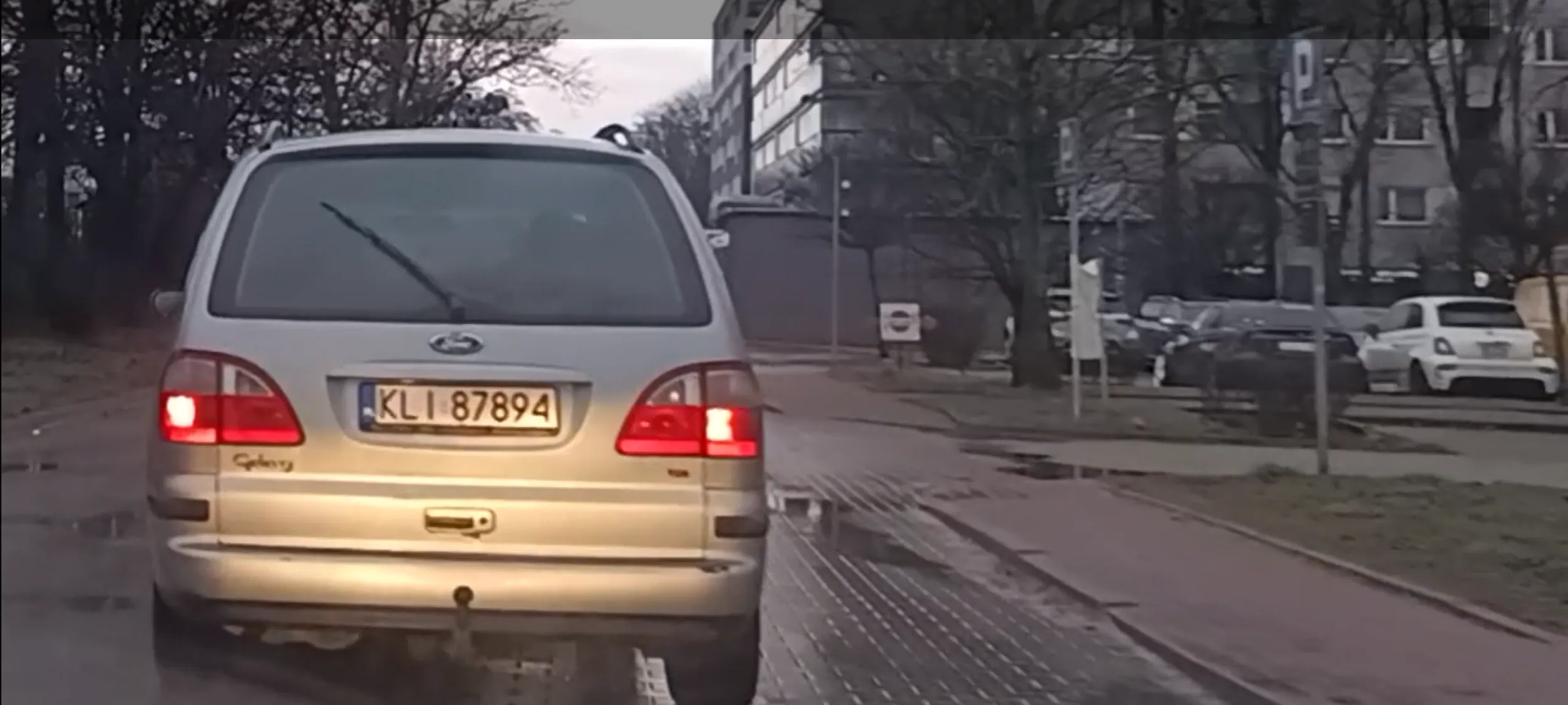 Kierujący w czasie jazdy rozmawia przez telefon komórkowy trzymany przy uchu.