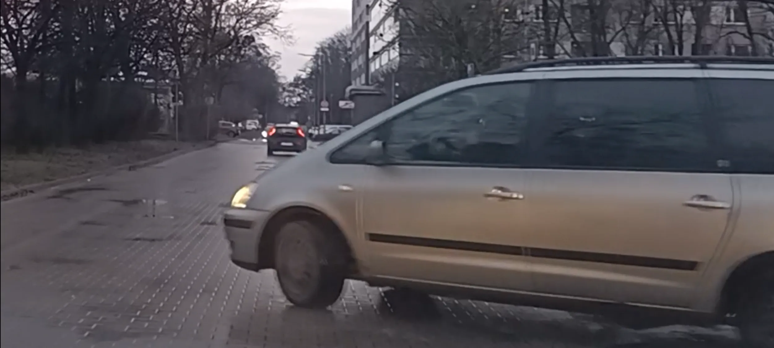 Kierujący w czasie jazdy rozmawia przez telefon komórkowy trzymany przy uchu.