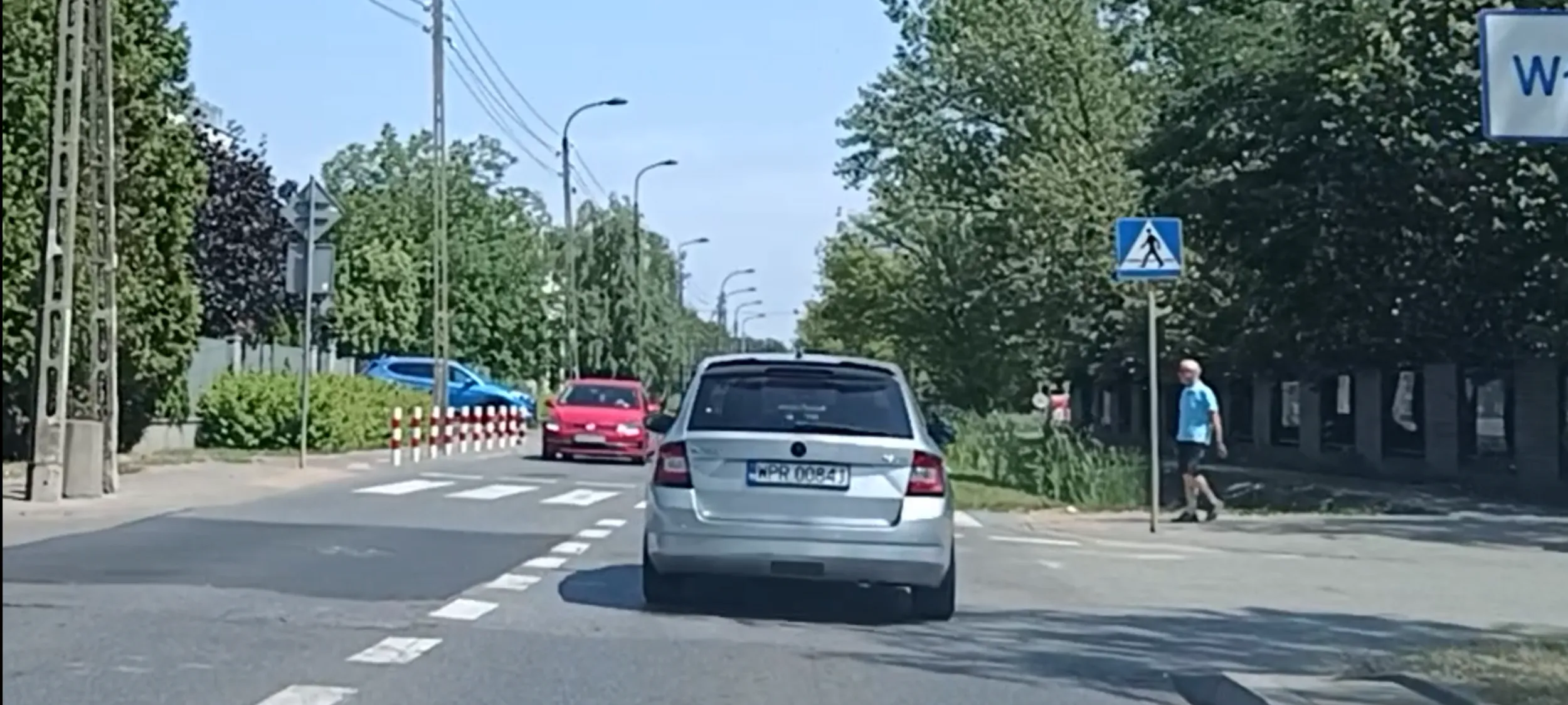 Bandyta drogowy w czerwonym wraku przejeżdża przez przejście dla pieszych i nie ustąpił pierwszeństwa pieszemu na przejściu w Warszawie