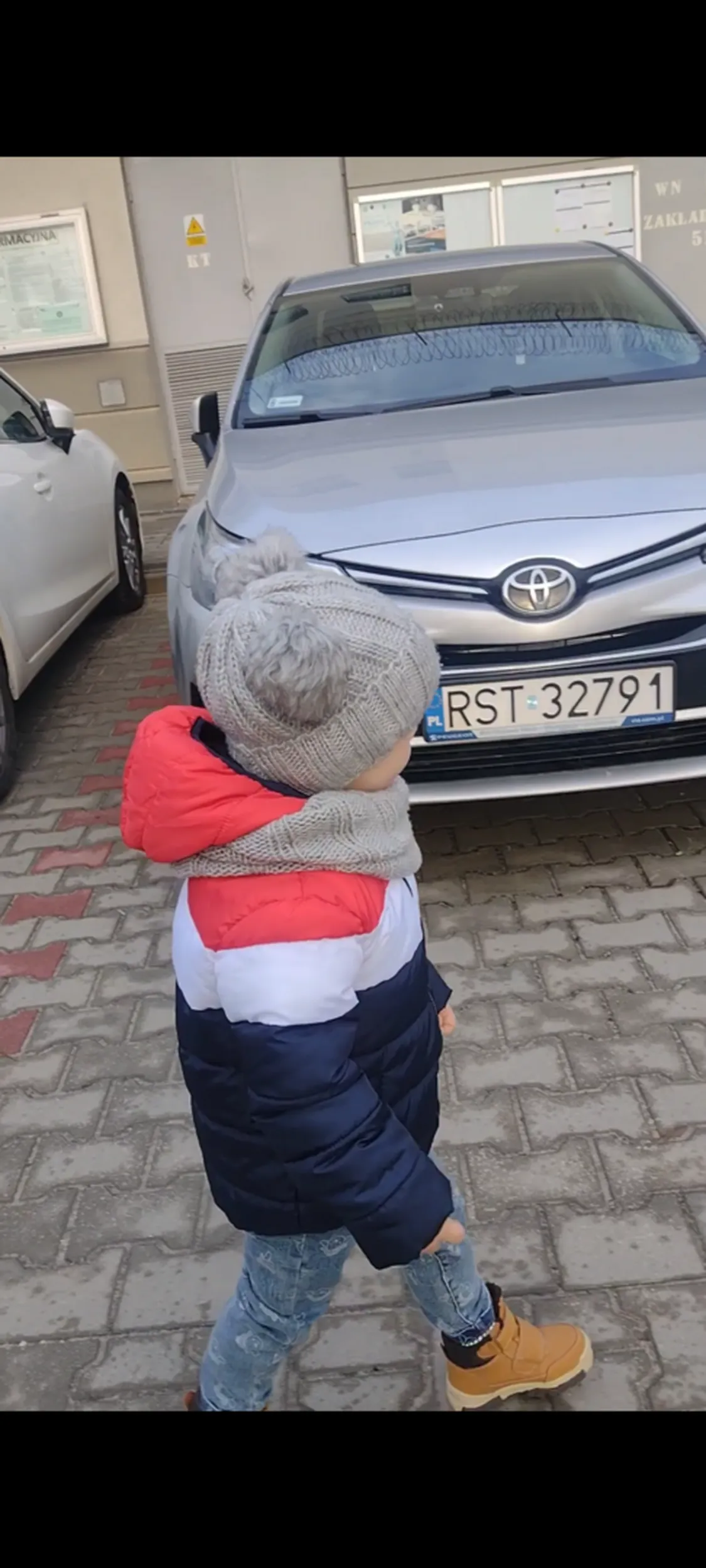 Dziecko przechodzi koło toyoty Auris hybrid chyba i to dziecko chyba wchodziło.          Do tego samochodu