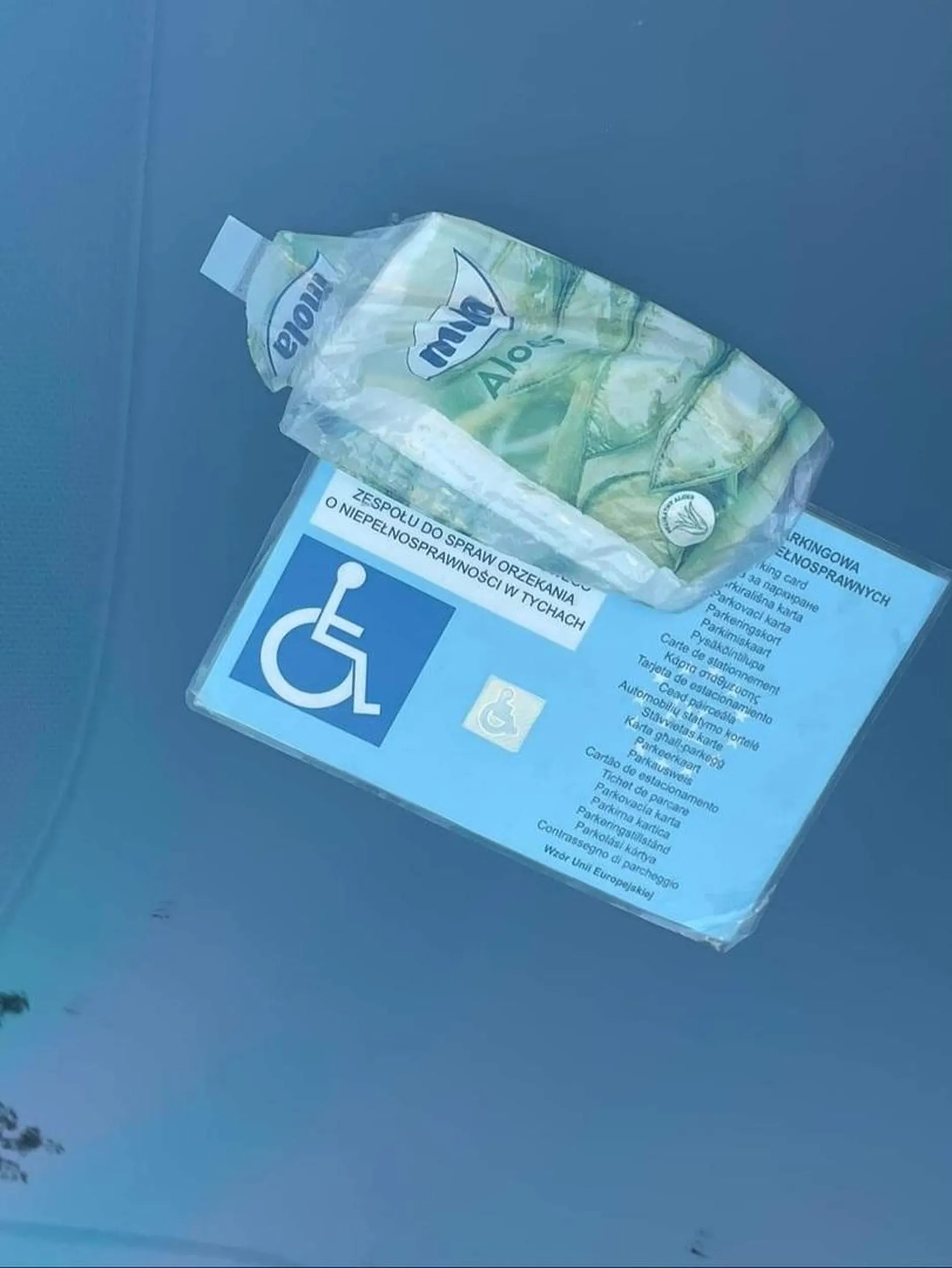 Oszust posługujący się nie swoją legitymacją osoby niepełnosprawnej. Bezczelnie parkuje na kopertach i wykłada pożyczoną legitymację zasłaniając dane.