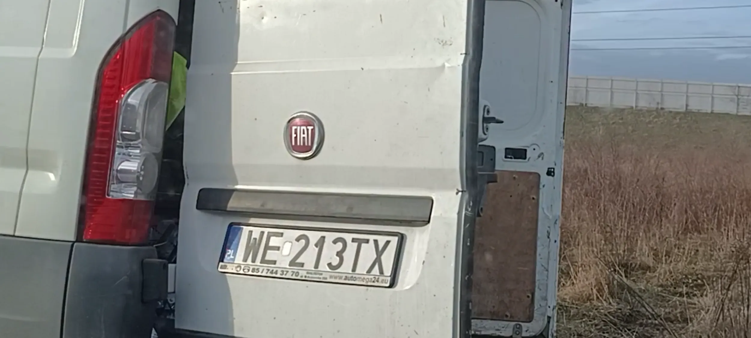 Auto stoi w błocie po zniszczonym trawniku przy ulicy gdzie jest zakaz zatrzymywania się i postoju