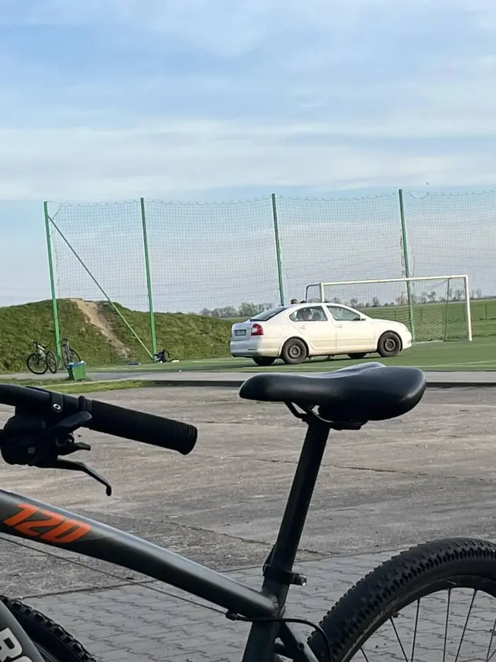 Nie pozdrawiam kierowca wjeżdża samochodem na boisko wykonane z sztucznej murawy.