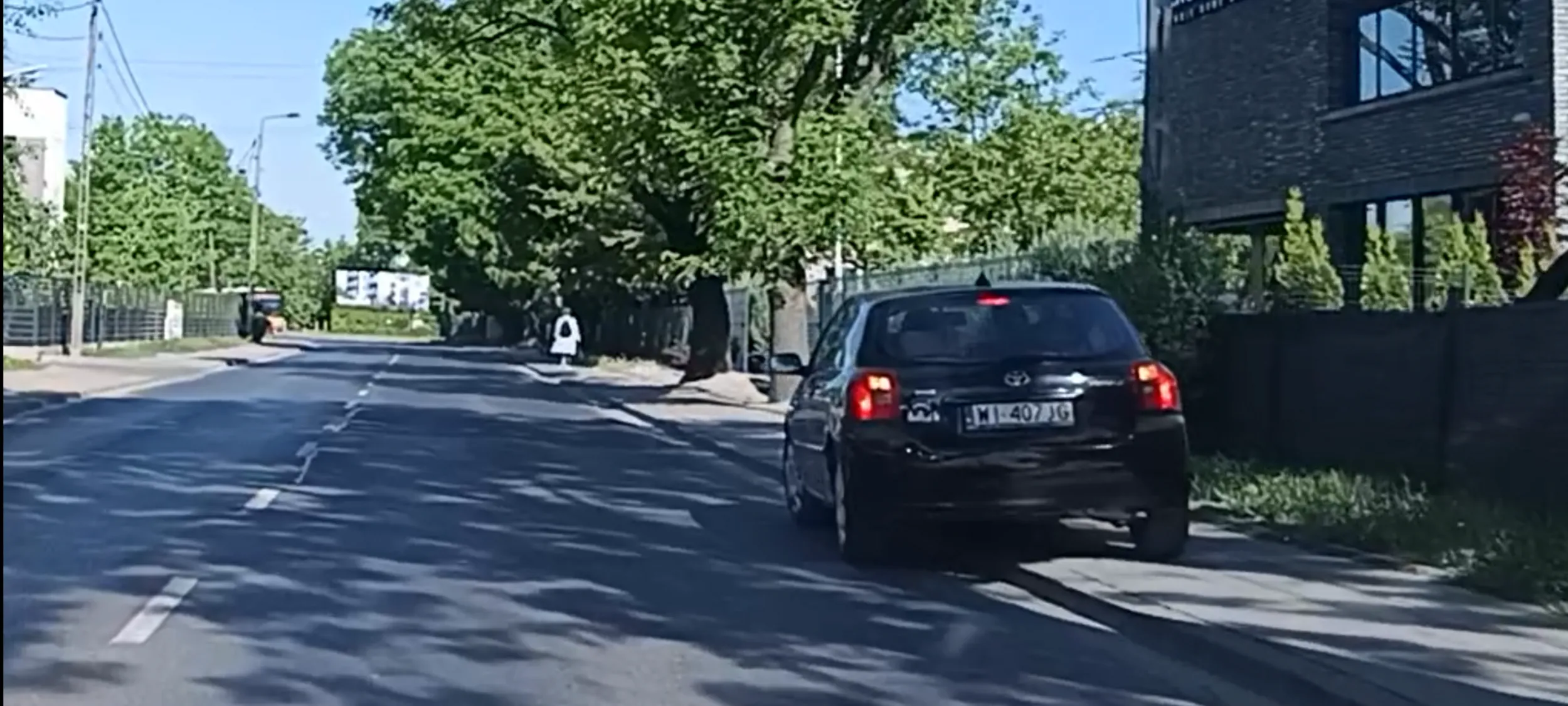Auto przeszkadza przechodniom w przejściu po chodniku. Pała, Jasiu, siadaj!