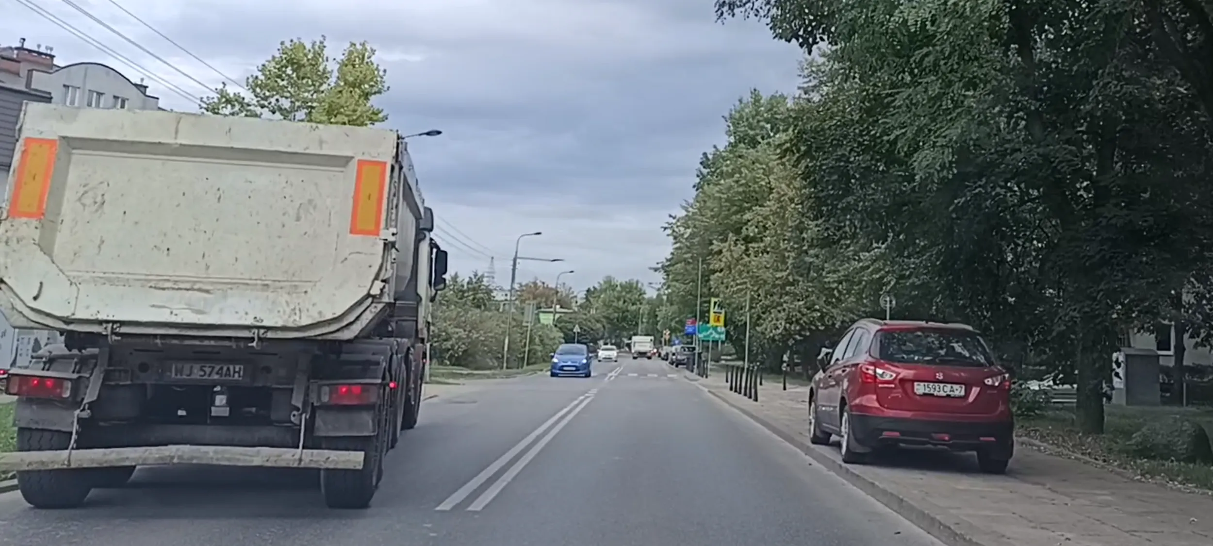 Pacan drogowy stanął pod budową pod prąd i na trawniku blokując jazdę ulicą.