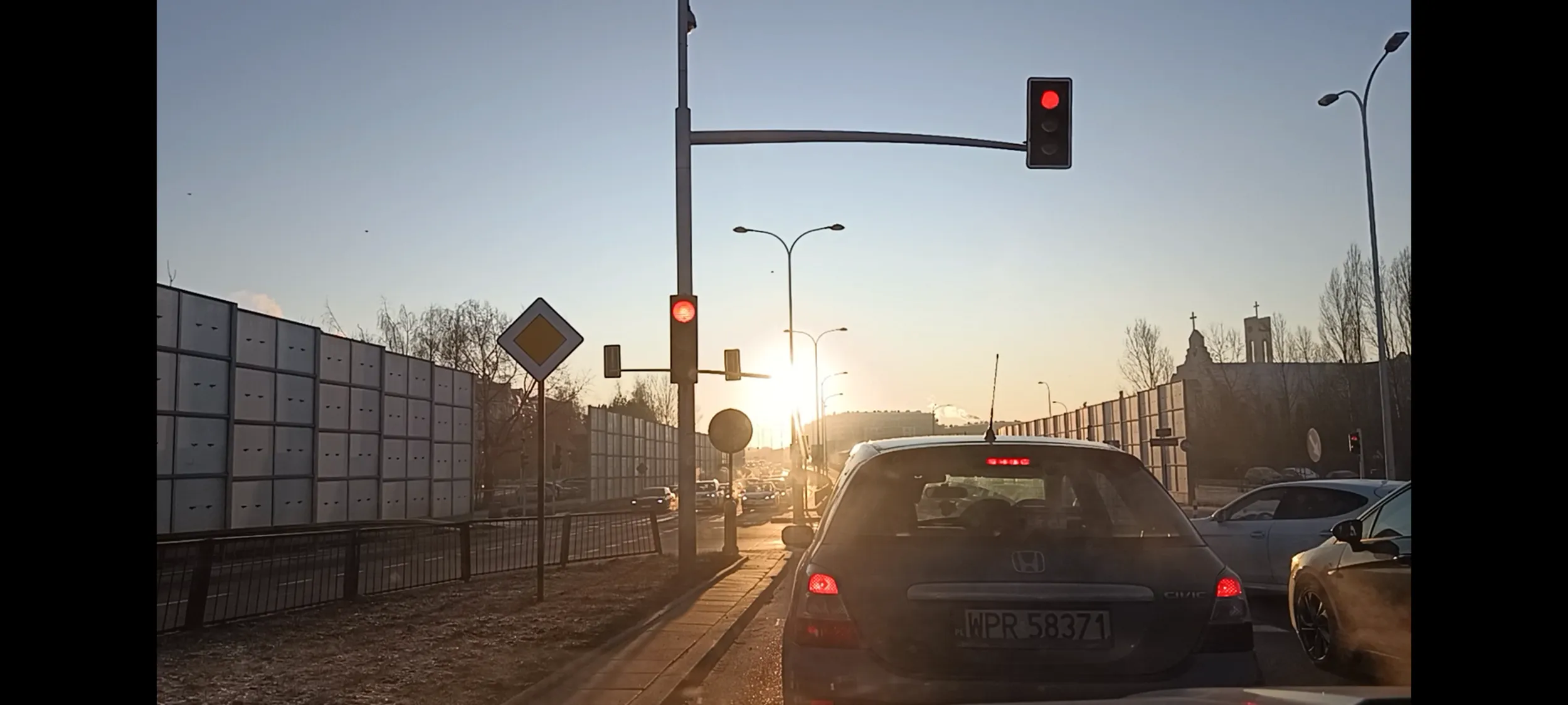 Prostak wpycha się z pasa do skrętu w lewo na pas do jazdy prosto za sygnalizator i przed stojące auta. To się kwalifikuje na wjazd na skrzyżowanie na czerwonym świetle, prostaku.