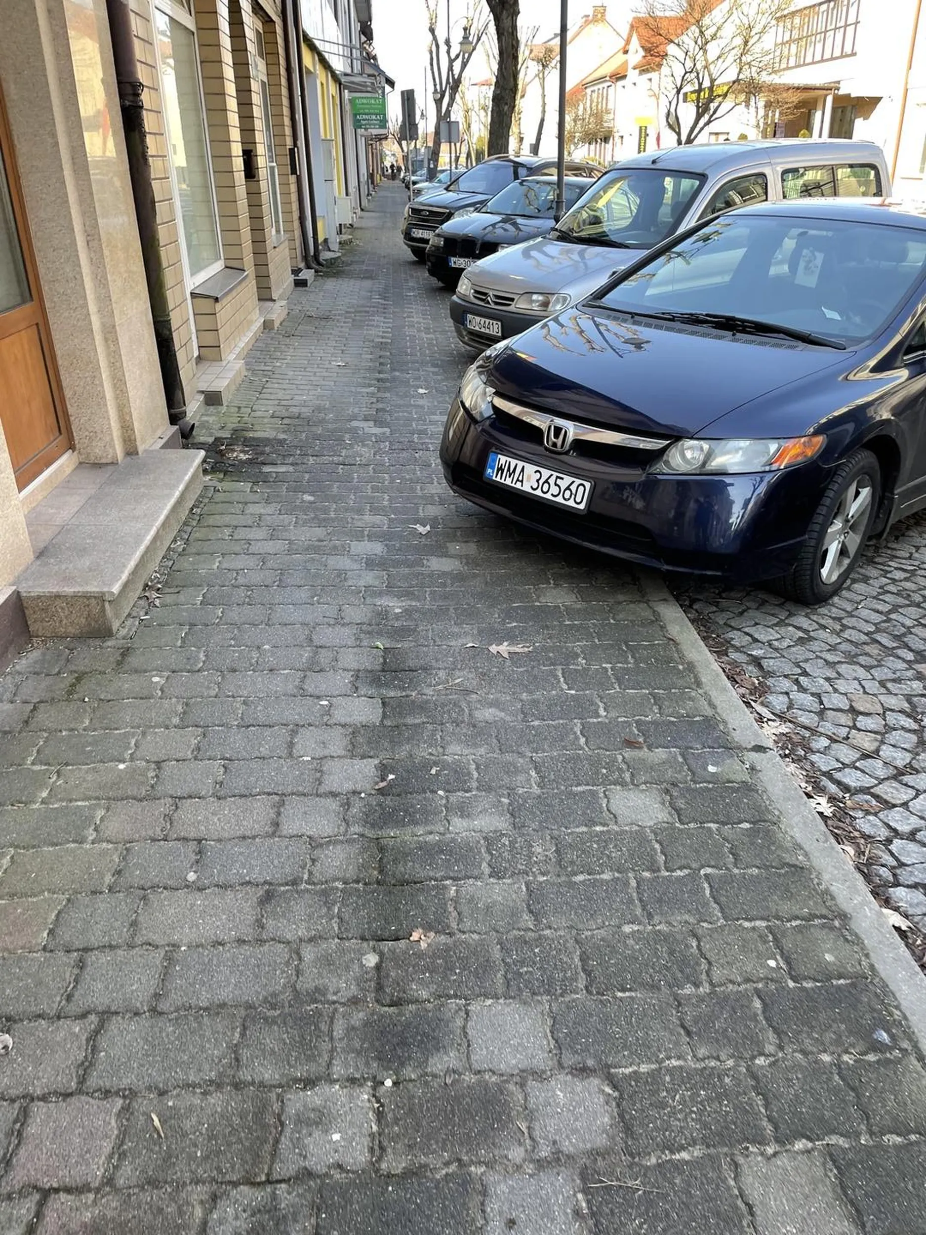 Pół chodnika dla pieszych zajęty przez samochód.