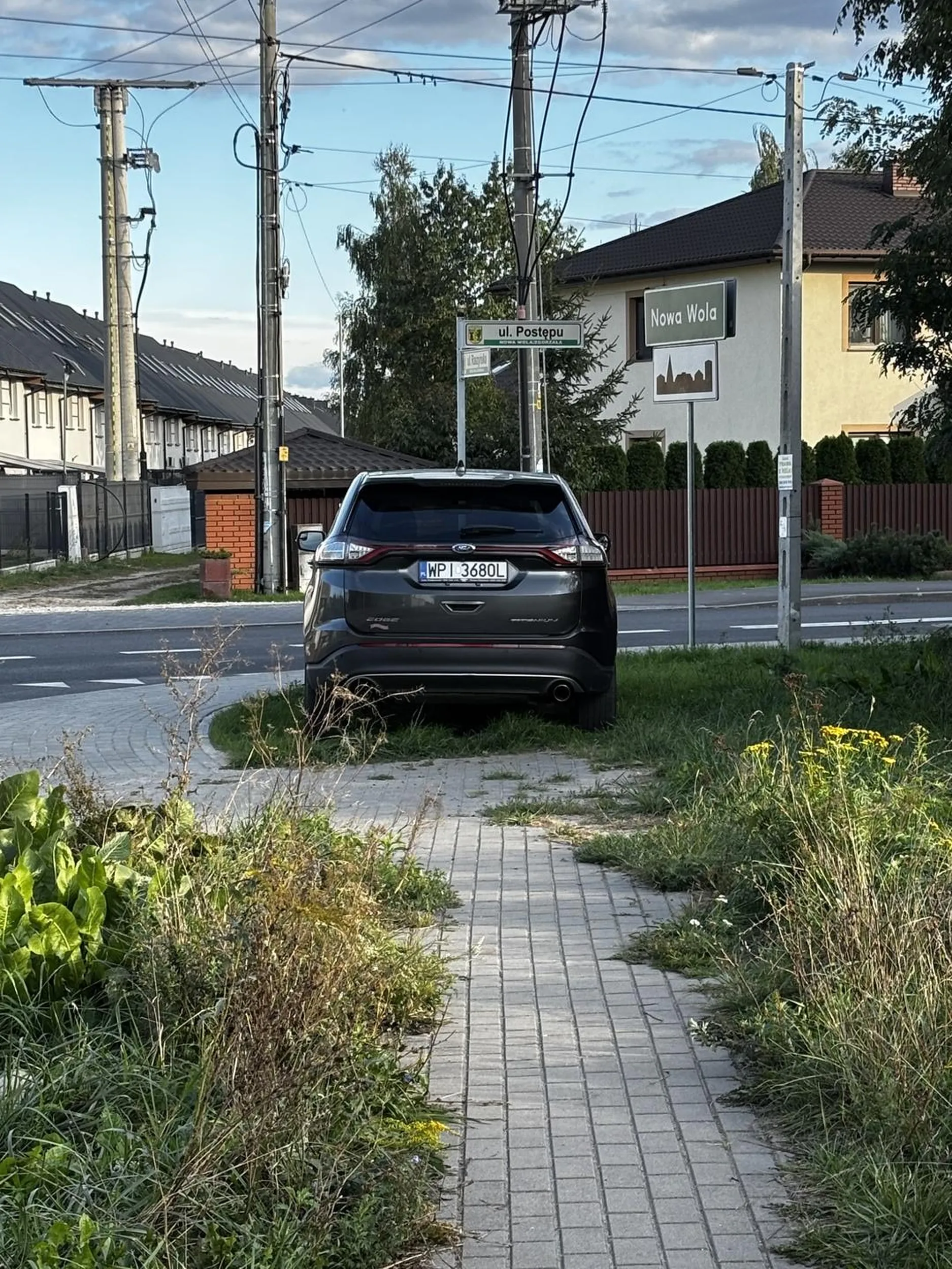 Wspaniały przykład niszczenia swojej okolicy.  Nowa trawa która urosła 2 tygodnie temu. Świeżo wyremontowana ulica. Trzeba postawić swoją bajadere na sprzedaż. Przejazd po pasach i chodniku, niszczenie zieleni, ograniczanie widoczności na skrzyżowaniu. Gratulacje ? jeszcze na? środku.
