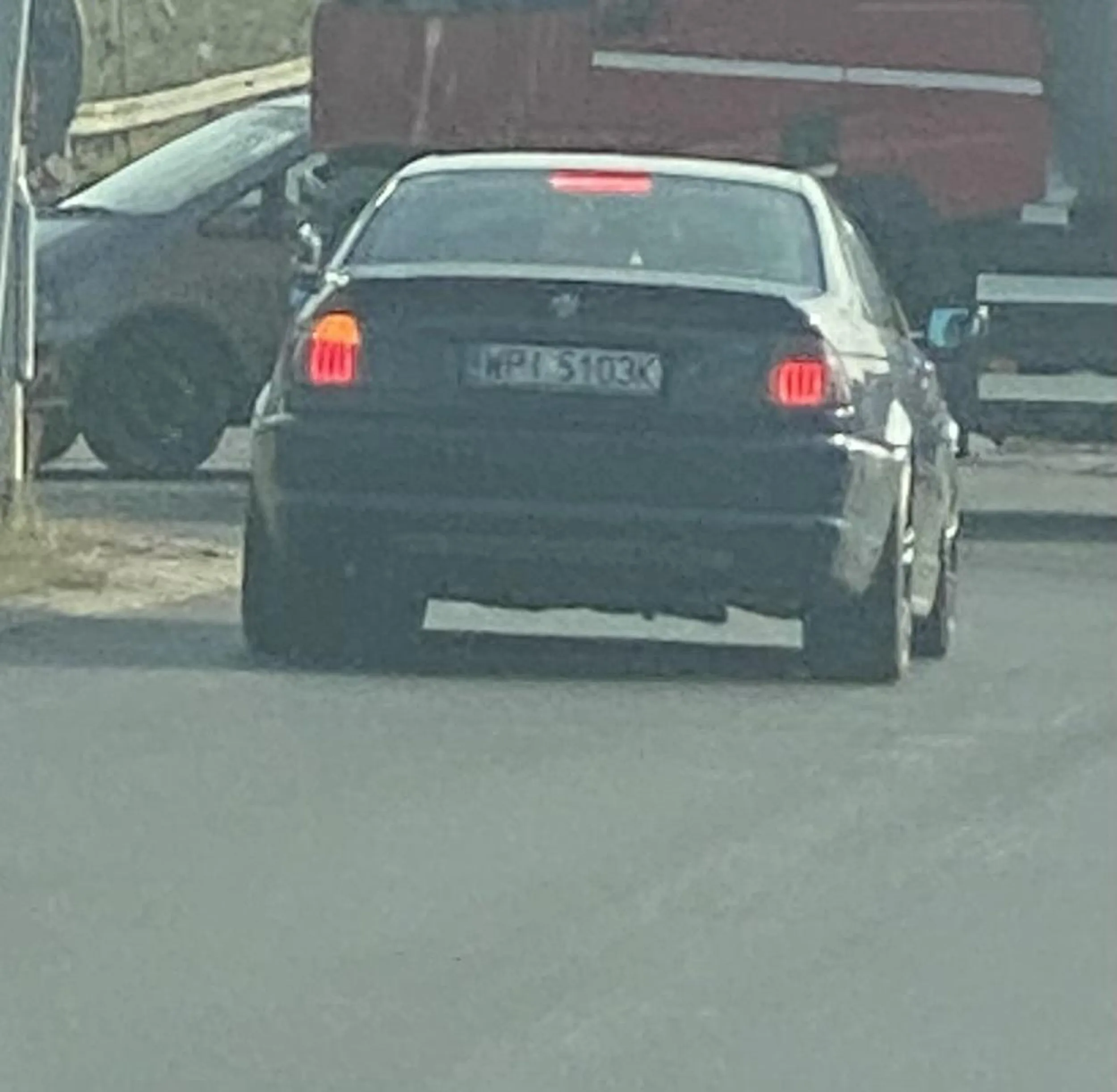 Szczyl podczas jazdy wyrzuca z samochodu śmieci i jakieś kamienie które lecą na szybę samochodów z tyłu