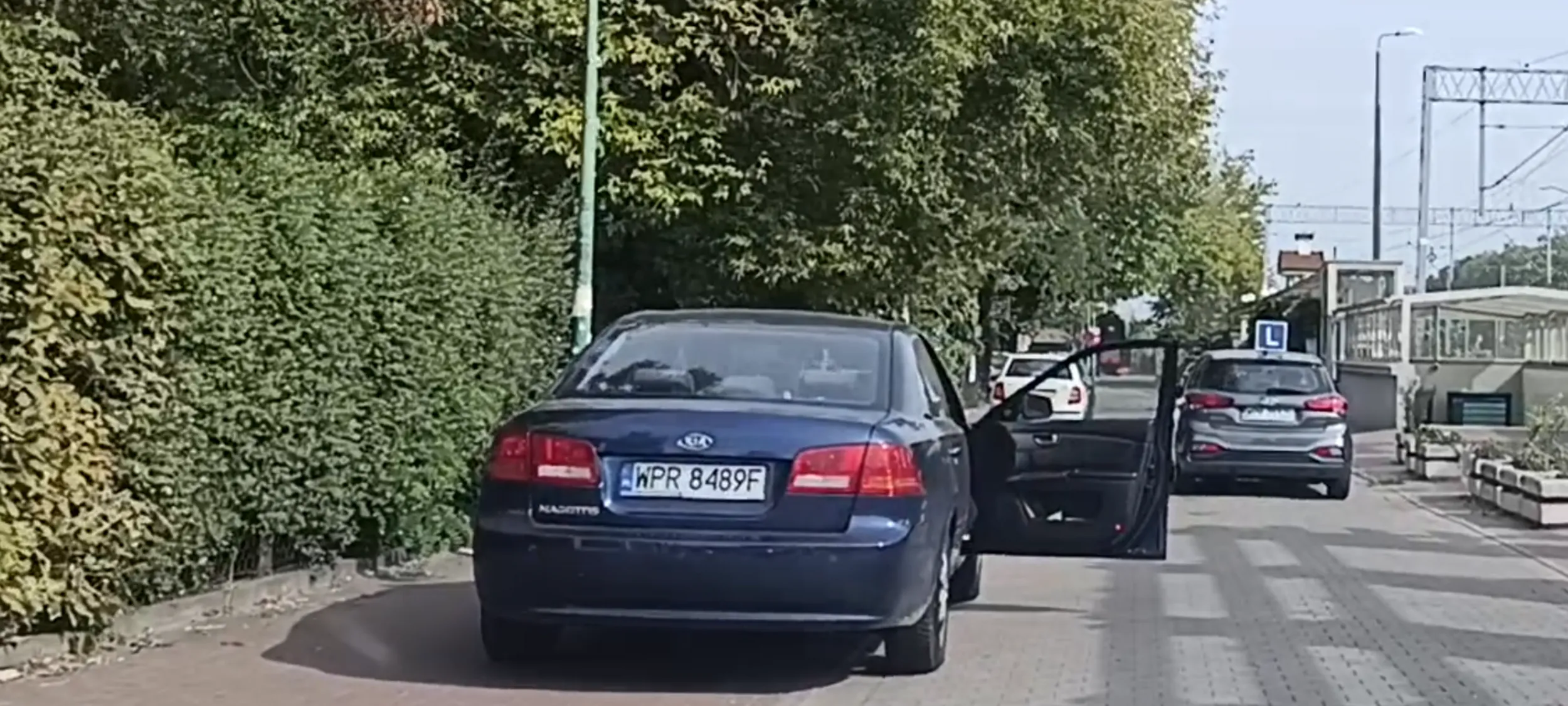 Babszczur z patokierowcą stoi na zakazie zatrzymywania się i postoju i blokuje przejazd zardzewiałymi drzwiami ze śladami po wypadku drogowym.