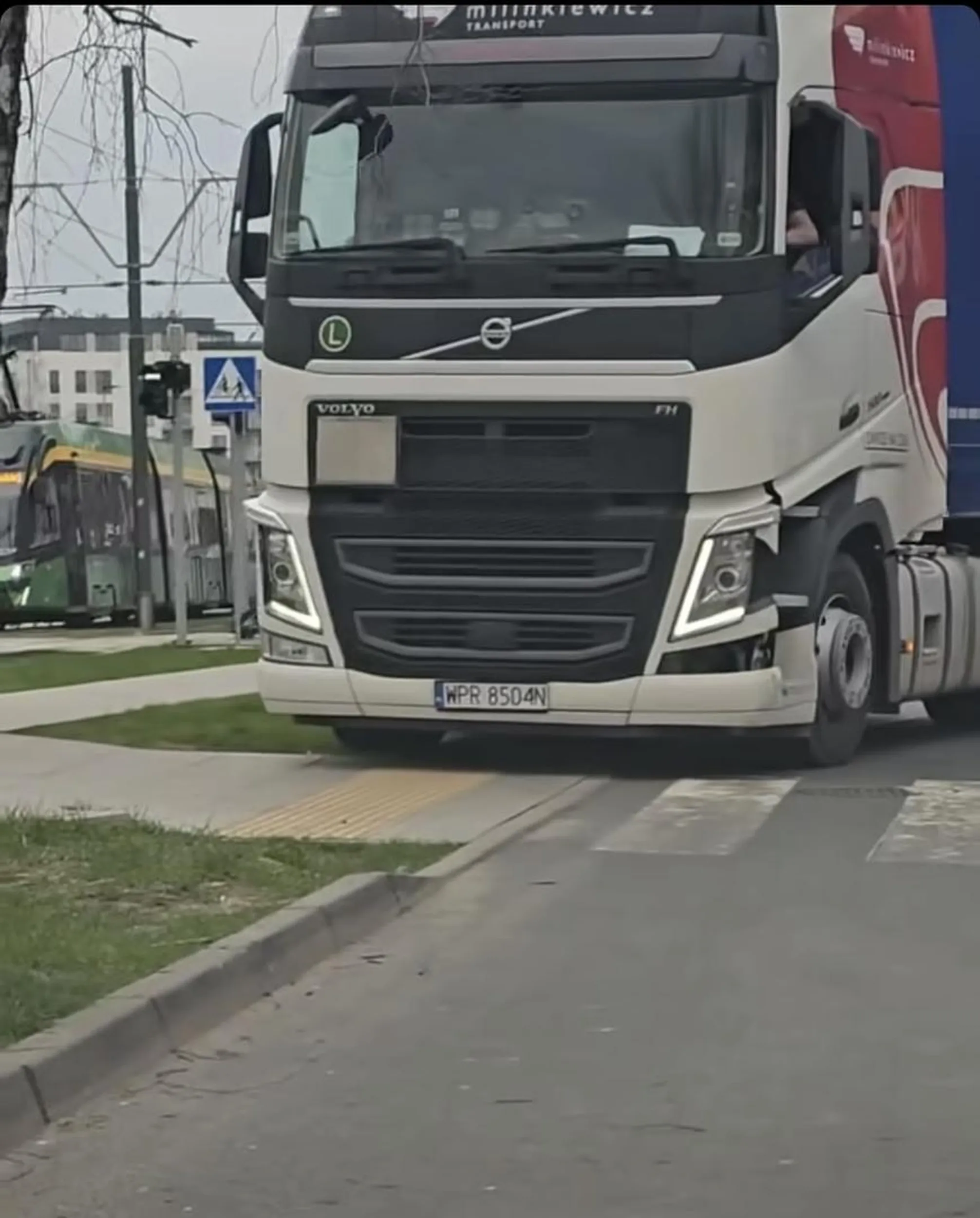 Kierowca jeździ po trawniku i chodniku ciężkim zestawem.