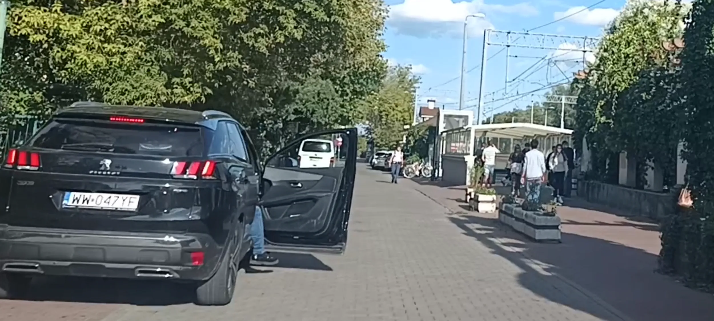 Patologia parkuje złomem po wypadku na chodniku i ulicy z zakazem zatrzymywania się i postoju, do tego blokuje przejazd otwartymi drzwiami. W środku 2 patodziadów pijących piwo.