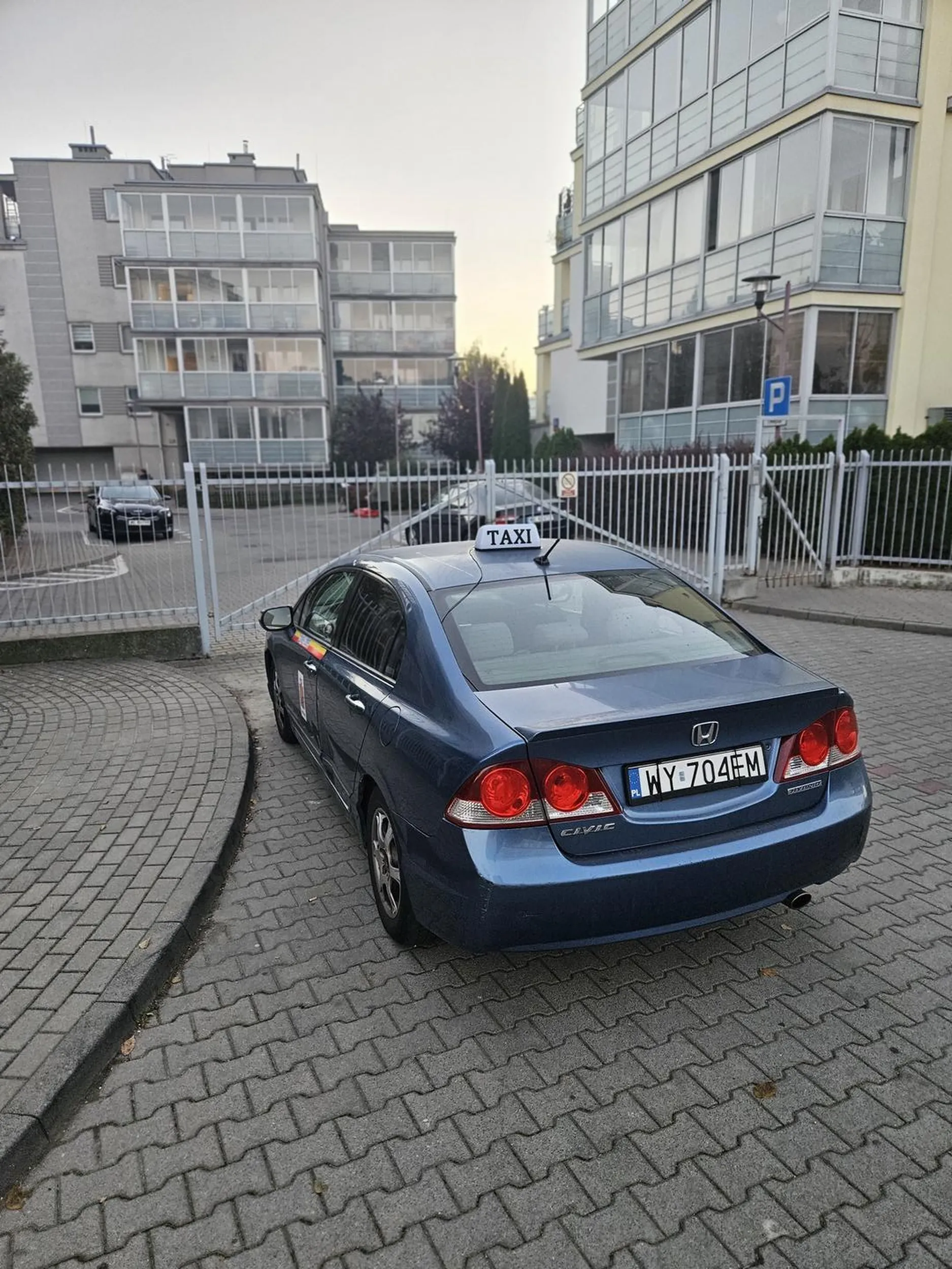 Nędzny grat Honda - taxówka zrobiła sobie stałe miejsce parkingowe przy Głębockiej 56a w Warszawie - na wjeździe do osiedla, blokując bramę pożarową.