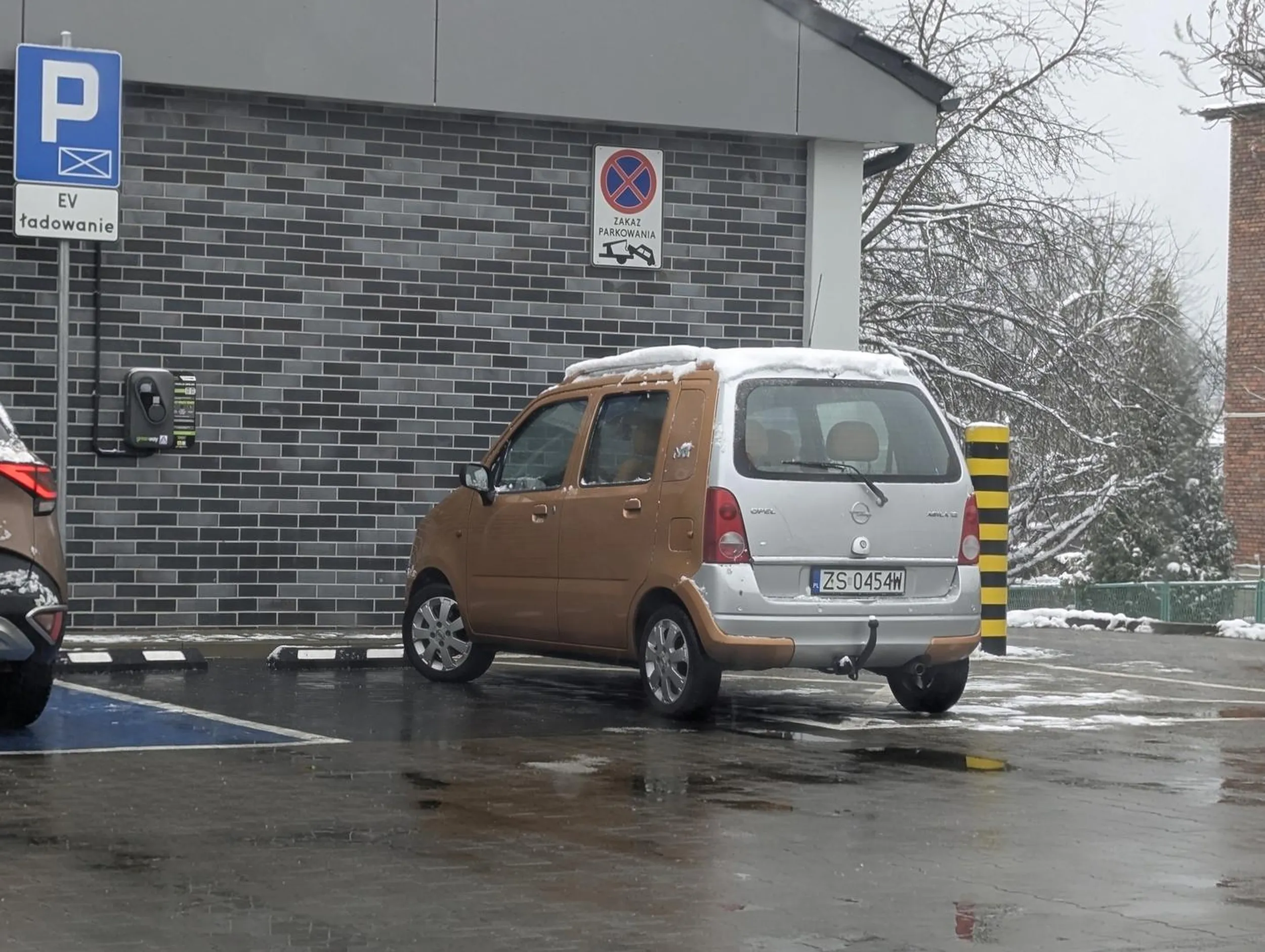 Pół elektryk z zimową czapką na dachu. Stanął w połowie na stanowisku do ładowania EV, a w drugiej połowie na zakazie. Do tego nie odśnieżony dach. Pozdrawiamy z Olkusza.