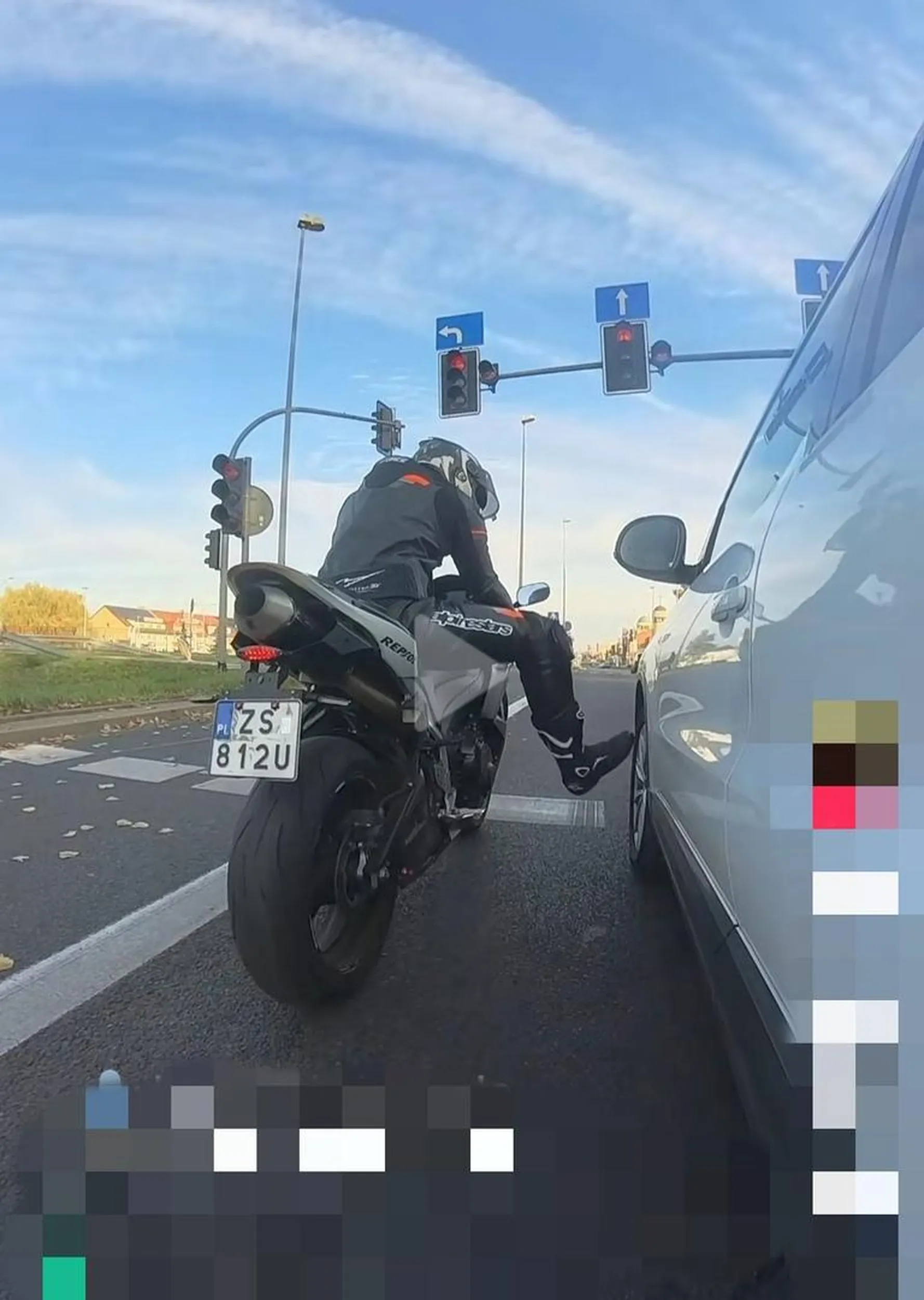 Pseudo motocyklista stojąc na światłach kopie w auto które stoi poprawnie na swoim pasie.