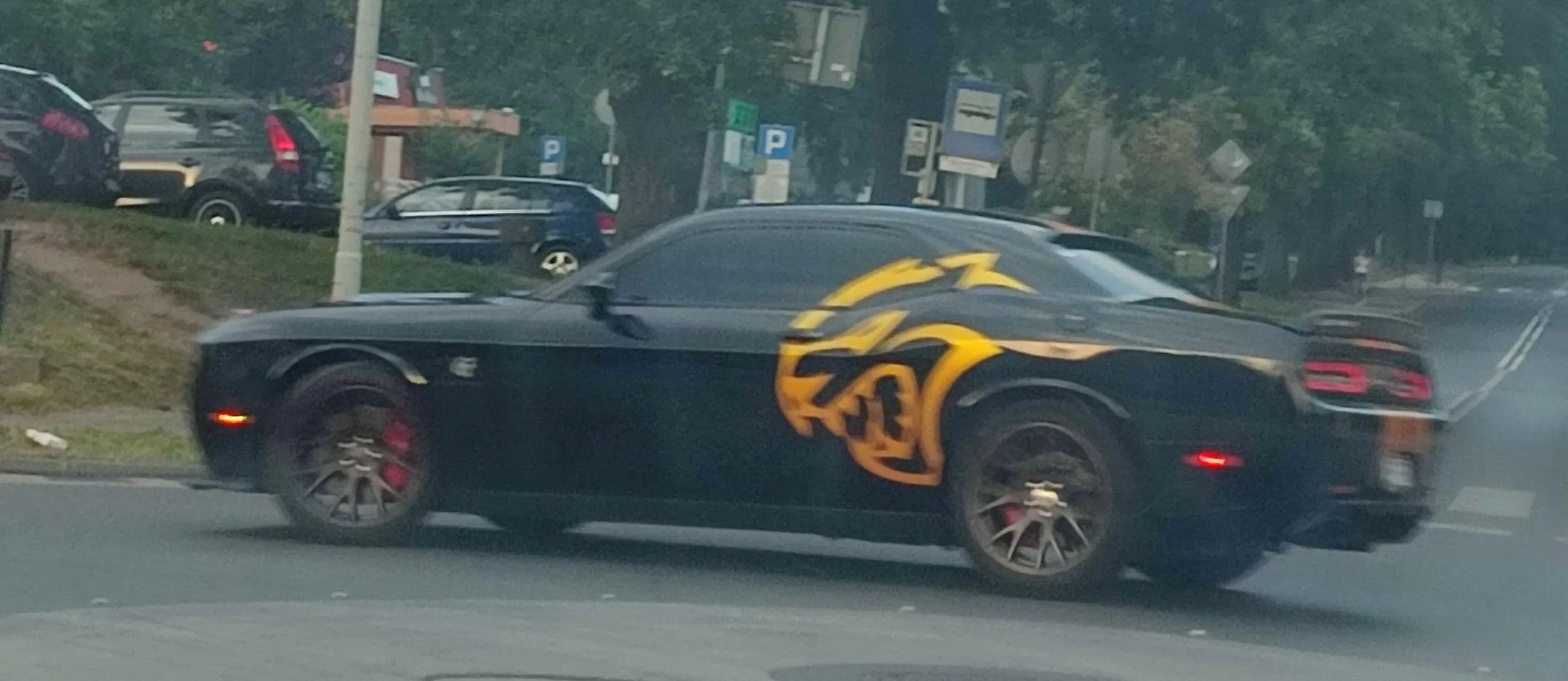 Dodge Challenger SRT Hellcat Czarny ze złotymi akcentami w postaci pasów na karoserii i dwóch złotych Hellcatów po jednym na lewym i prawym boku.