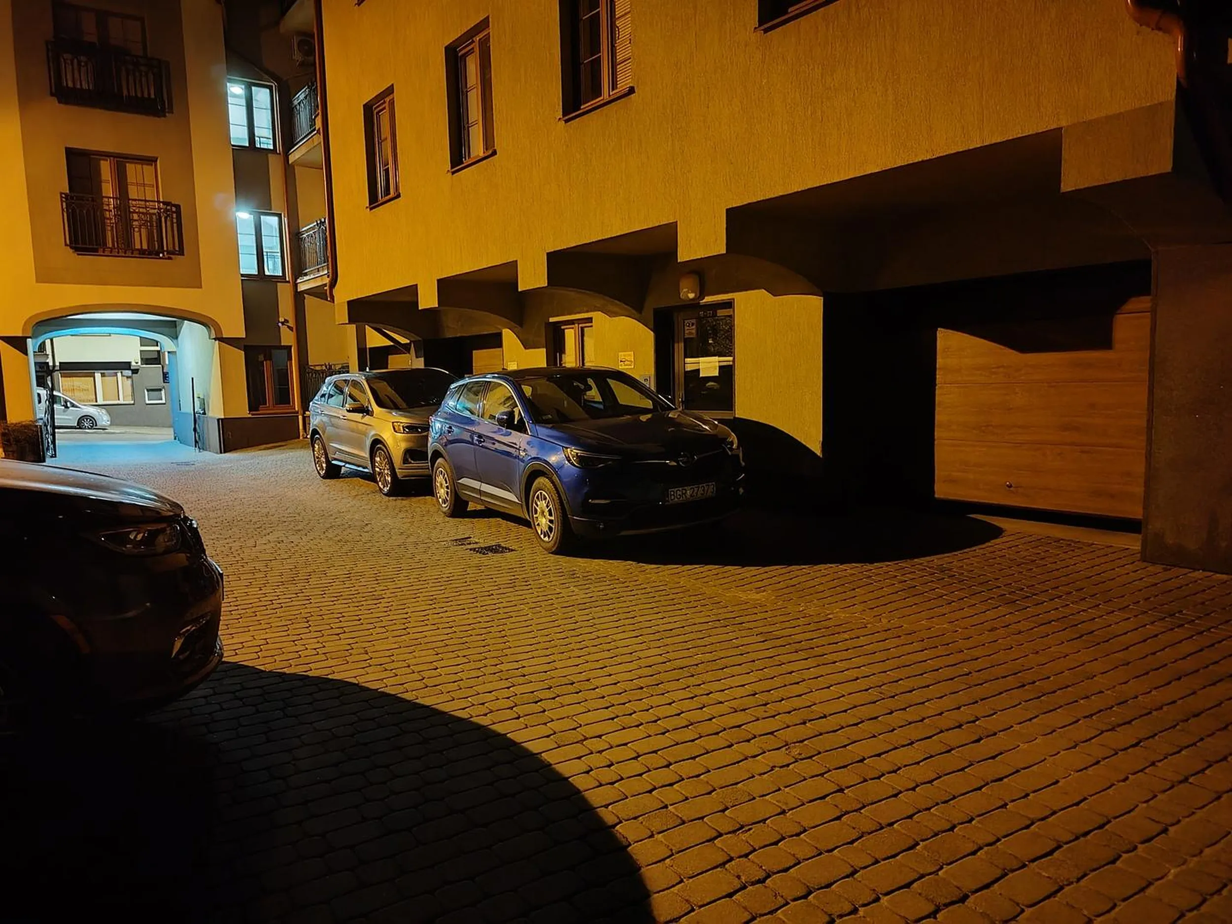 Samochód zaparkowany bezpośrednio przy drzwiach klatki schodowej.