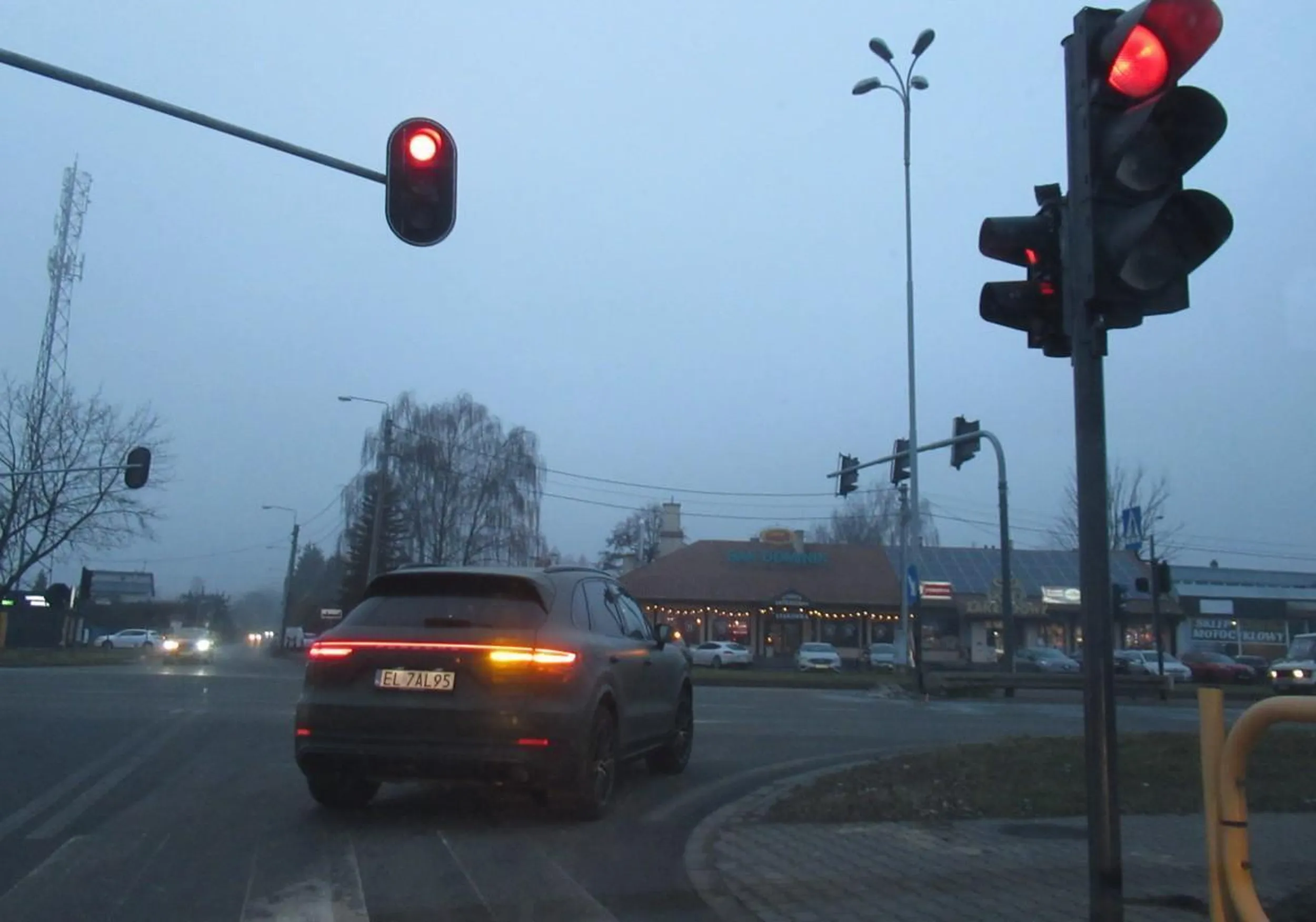Cham w porsche omija kolejkę przed sygnalizacją świetlną przekraczając podwójną ciągła linię i wjeżdża na skrzyżowanie na czerwonym świetle.