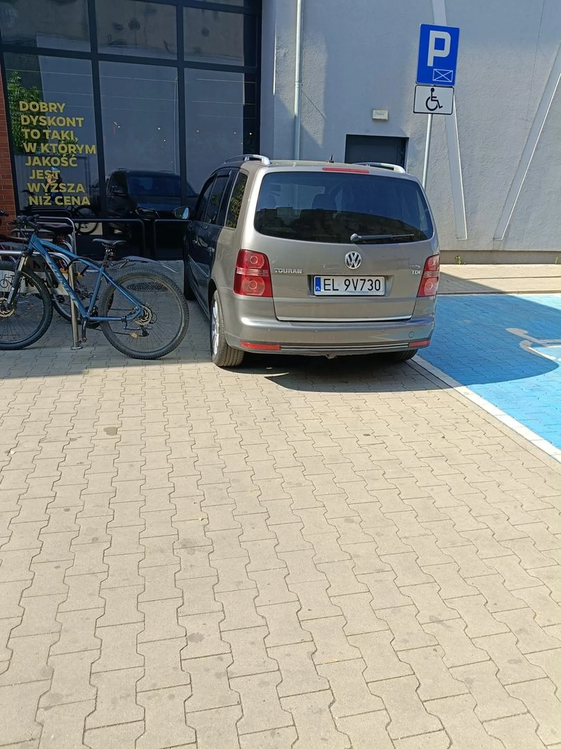 Mimo miejsca na pustym parkingu po prawo, kierujący parkuje jak najbliżej wejścia w miejscu nie wyznaczonym blokując dojście do stojaka na rowery.