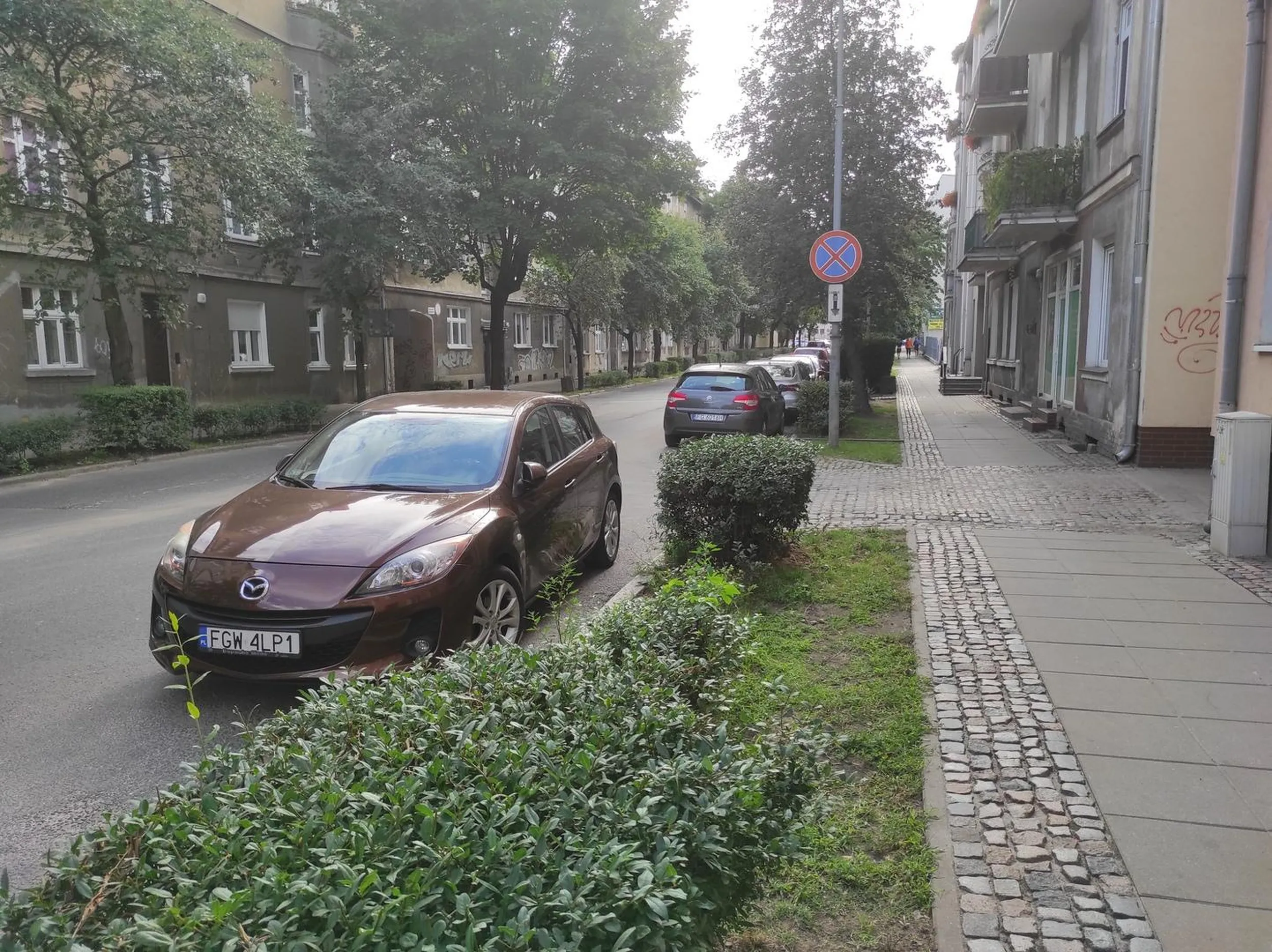 Utrudnia wyjazd z bramy, parkuje na zakazie, staje pod prąd. Gorzów Wielkopolski, ul. Mickiewicza. Podstawa prawna: par.28 ust.2 ustawy o znakach drogowych - złamany zakaz zatrzymywania się i postoju (znak b-36 widoczny na zdjęciu). art.49 ust.2 pkt.1 ustawy prawo o ruchu drogowym - postój utrudnia wyjazd z bramy, zasłania wyjeżdzającym drogę ul. Mickiewicza. art.49 ust.1 pkt.7 ustawy prawo o ruchu drogowym: zabrania się zatrzymywania pojazdu na jezdni przy jej lewej krawędzi.