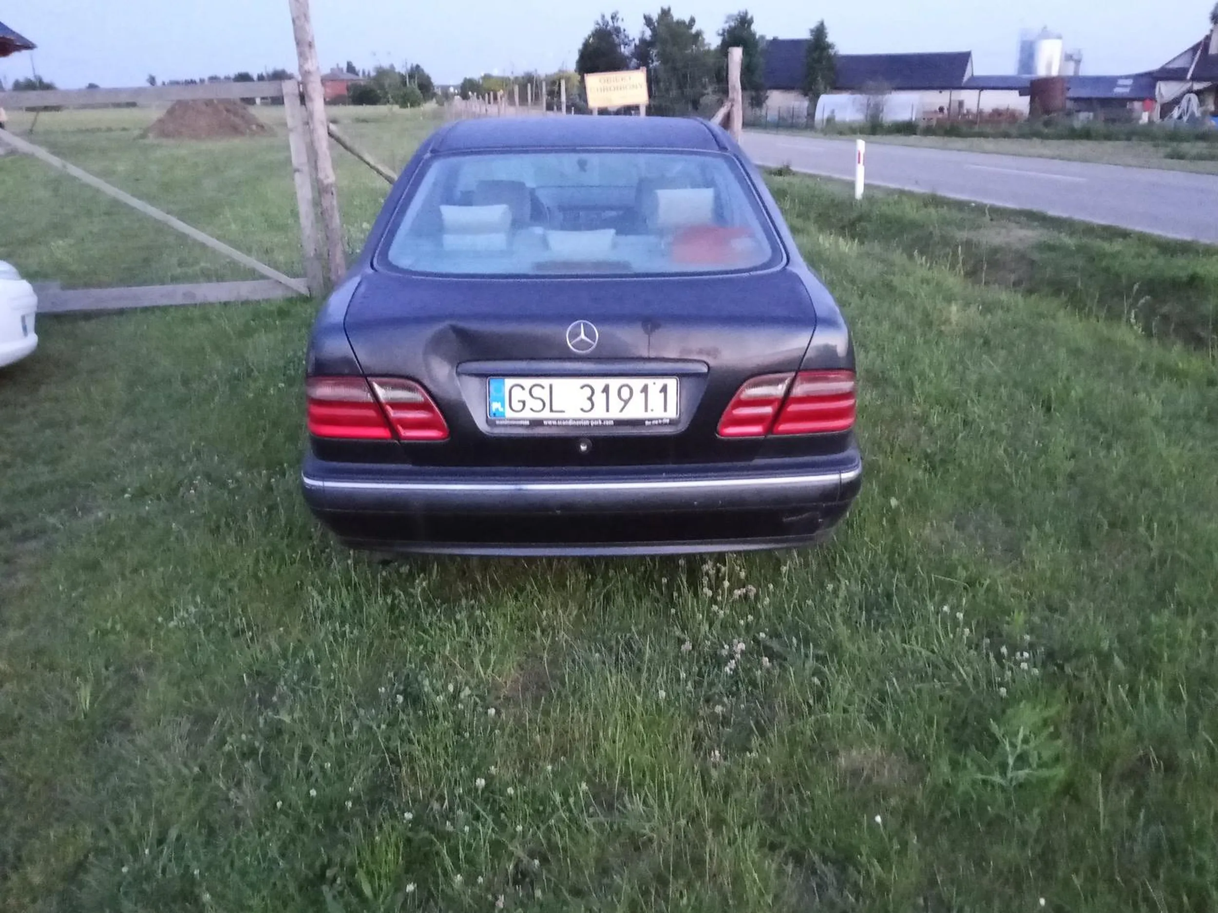 Mercedes stoi pod bramą domu na działce, auto wygląda podejrzanie w środku jest bajzer i jakieś nożyce.