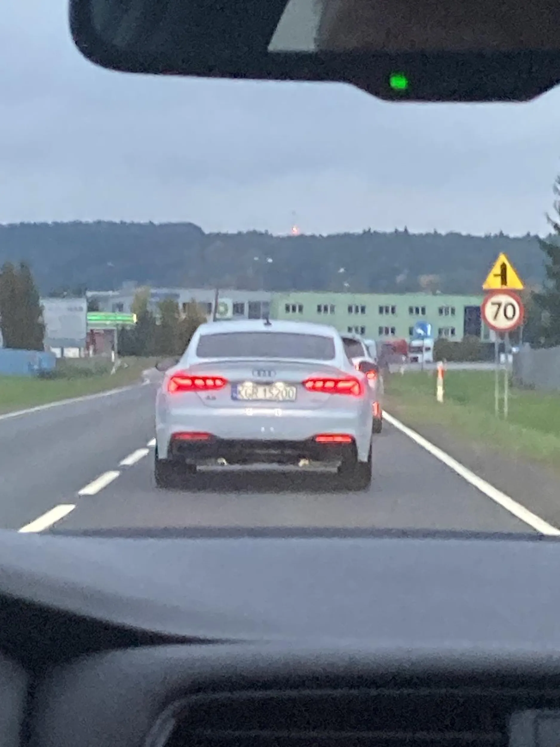 Białe Audi A5 wyprzedza na podwójnej ciągłej na zakręcie i stwarza nie małe zagrożenie na stronie.