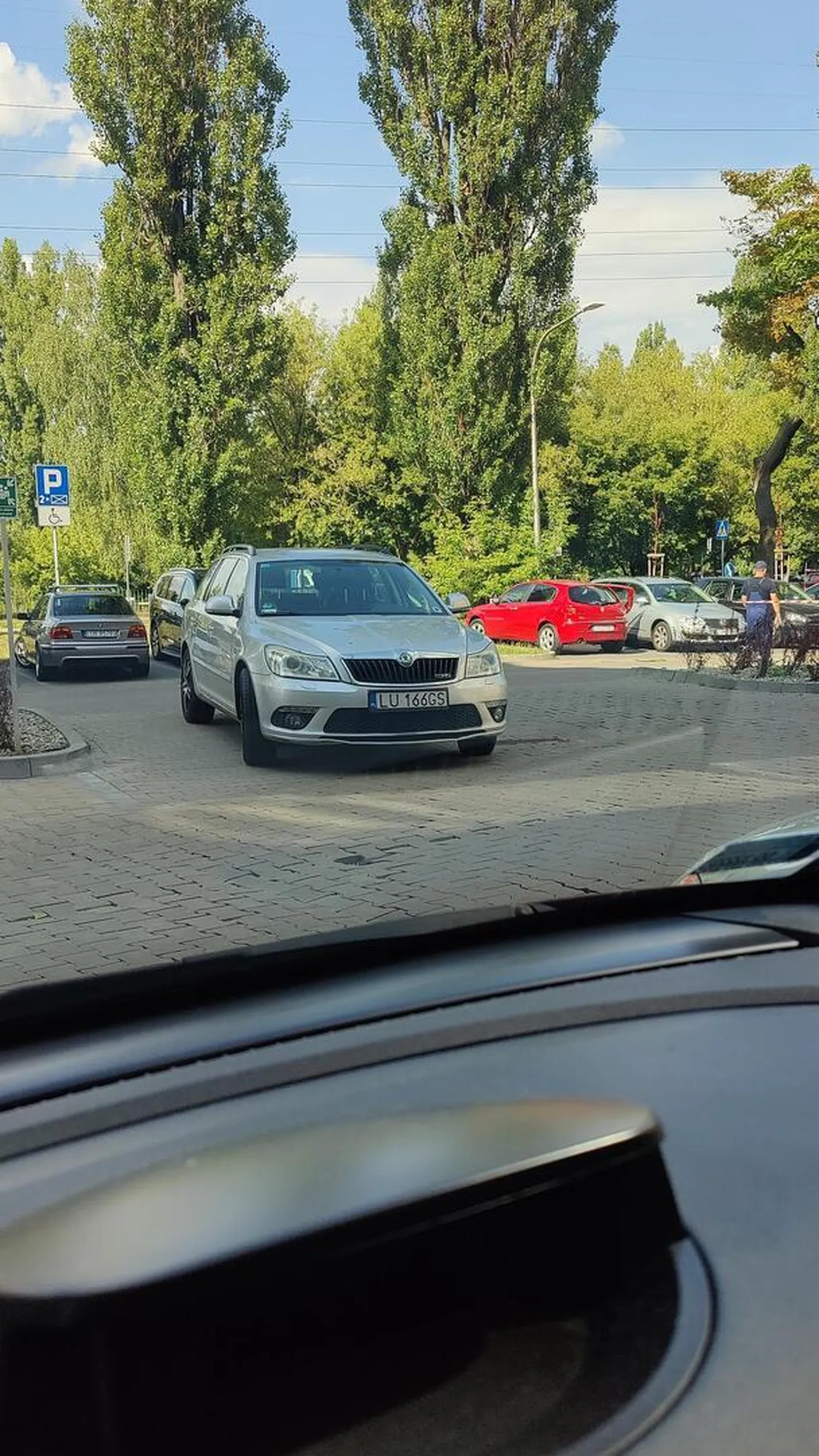 Facet parkuje na środku wjazdu na parking.