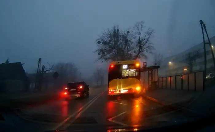 Poznań. Mitsubishi wymija na podwójnej ciągłej autobus na przystanku.