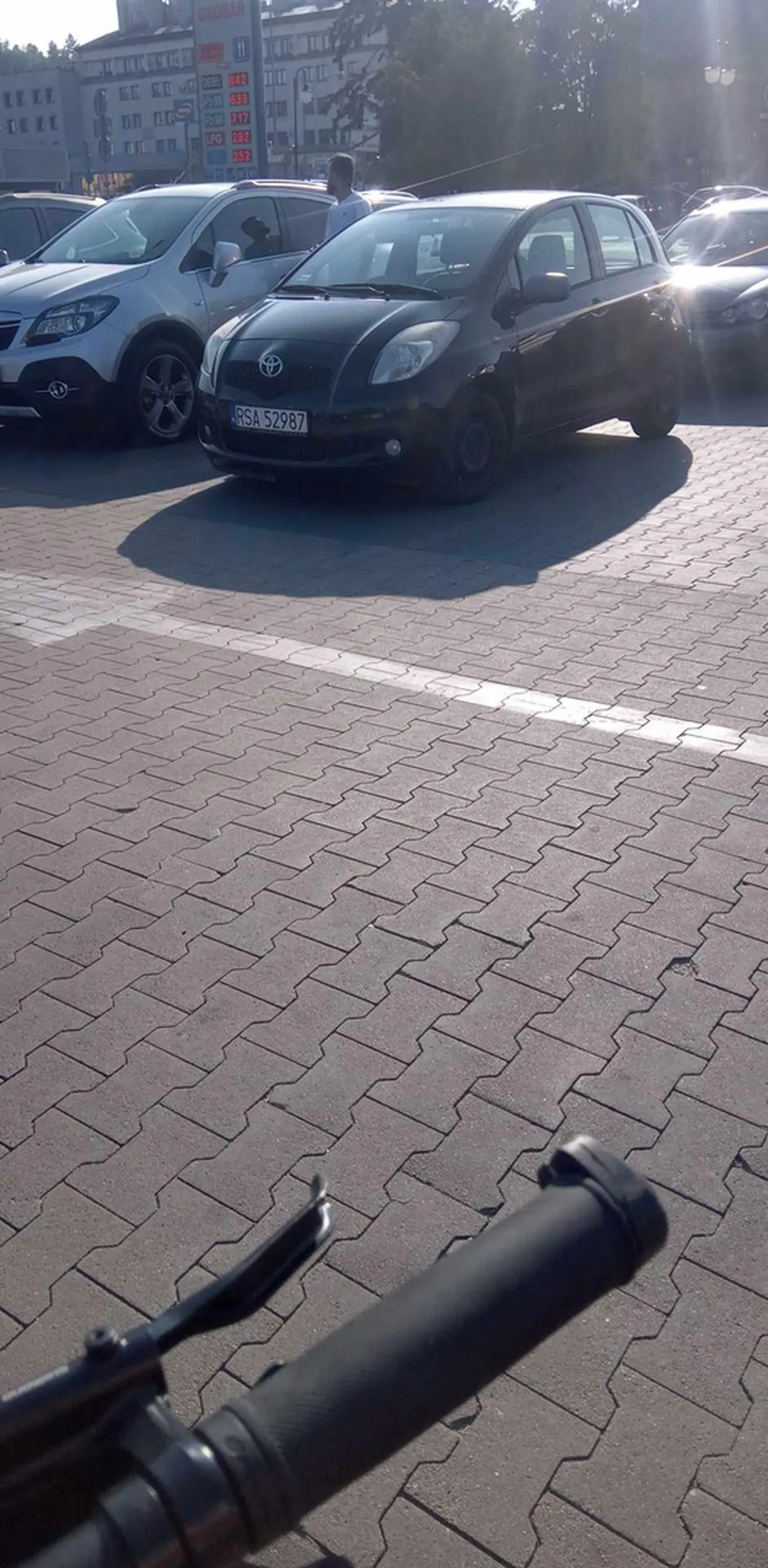 Tojota Yaris dwa Silnik VVTI Jakuba C.  stoi pod kauflandem  który ubiera garnitur