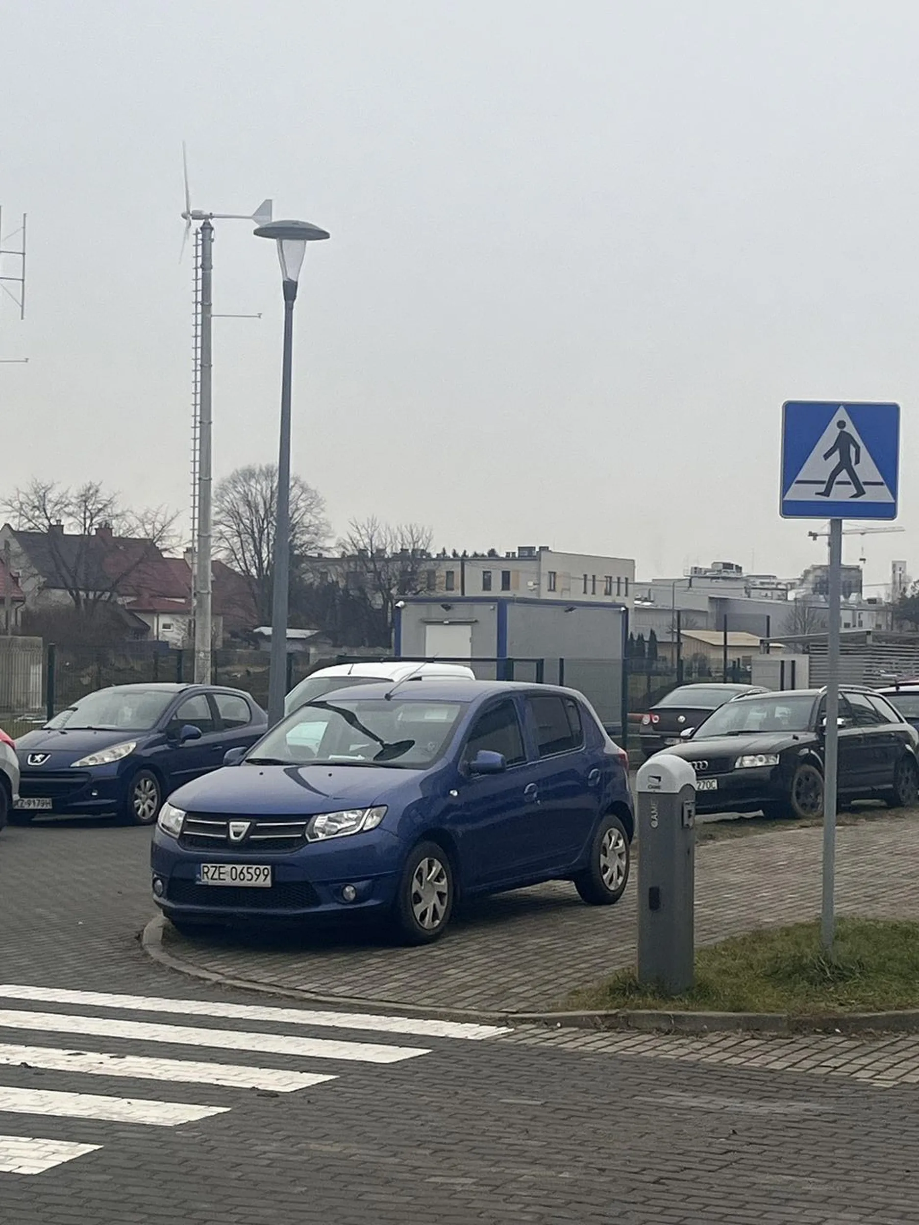 Kierowca nieprawidłowo zaparkował samochód na zdjęciu. Pojazd stoi częściowo na chodniku oraz bezpośrednio przy przejściu dla pieszych, co jest niezgodne z przepisami ruchu drogowego. Takie ustawienie pojazdu utrudnia ruch pieszym i może stwarzać zagrożenie dla bezpieczeństwa.
